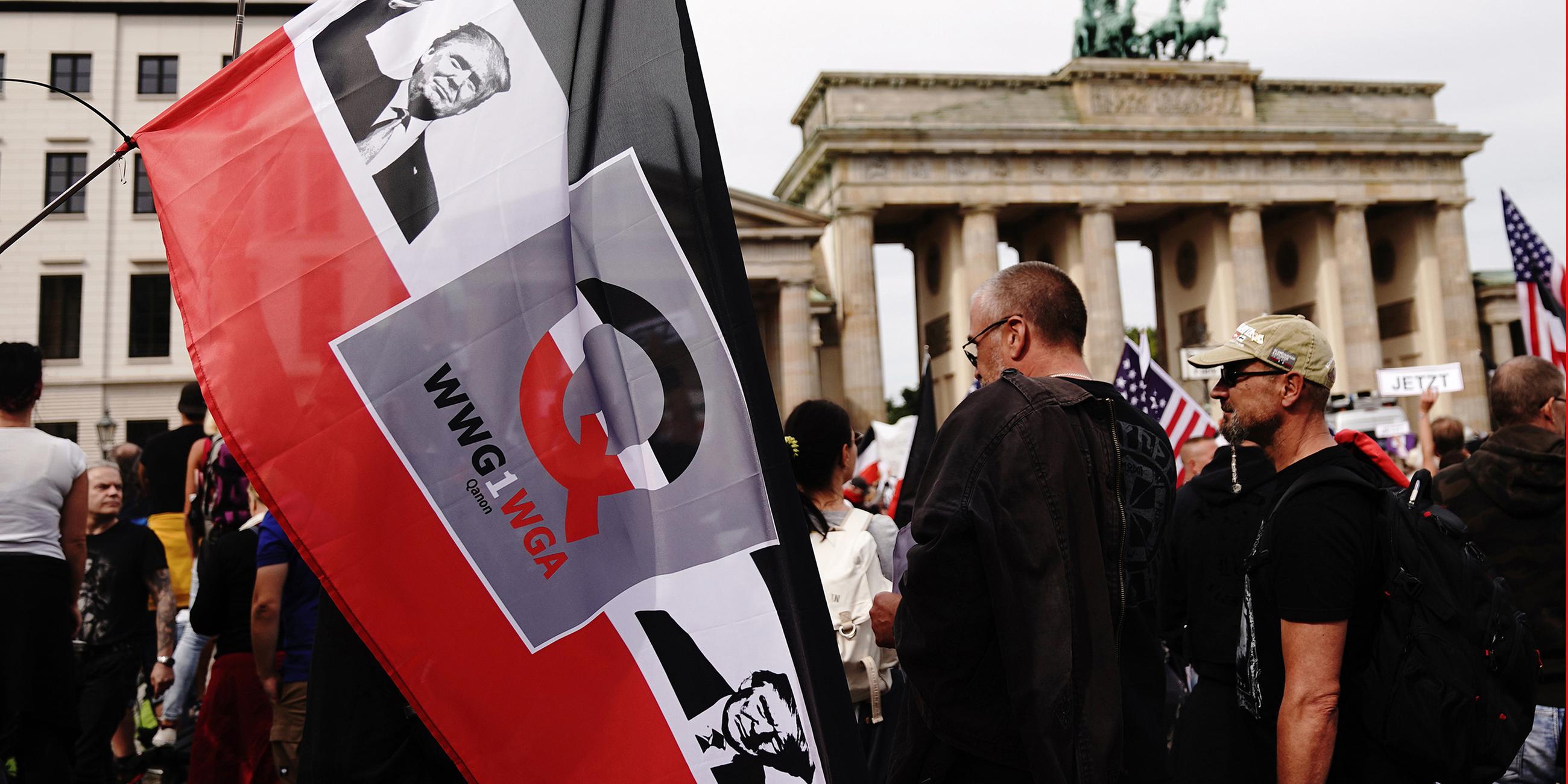 Archiv, Berlin: Auf einer schwarzweissroten Fahne, die ein Teilnehmer vor dem Brandenburger Tor hält, sind ein Bild von US Präsident Trump, der Buchstabe "Q" sowie der Schriftzug "WWG1WGA" (where we go one, we go all) aufgedruckt.