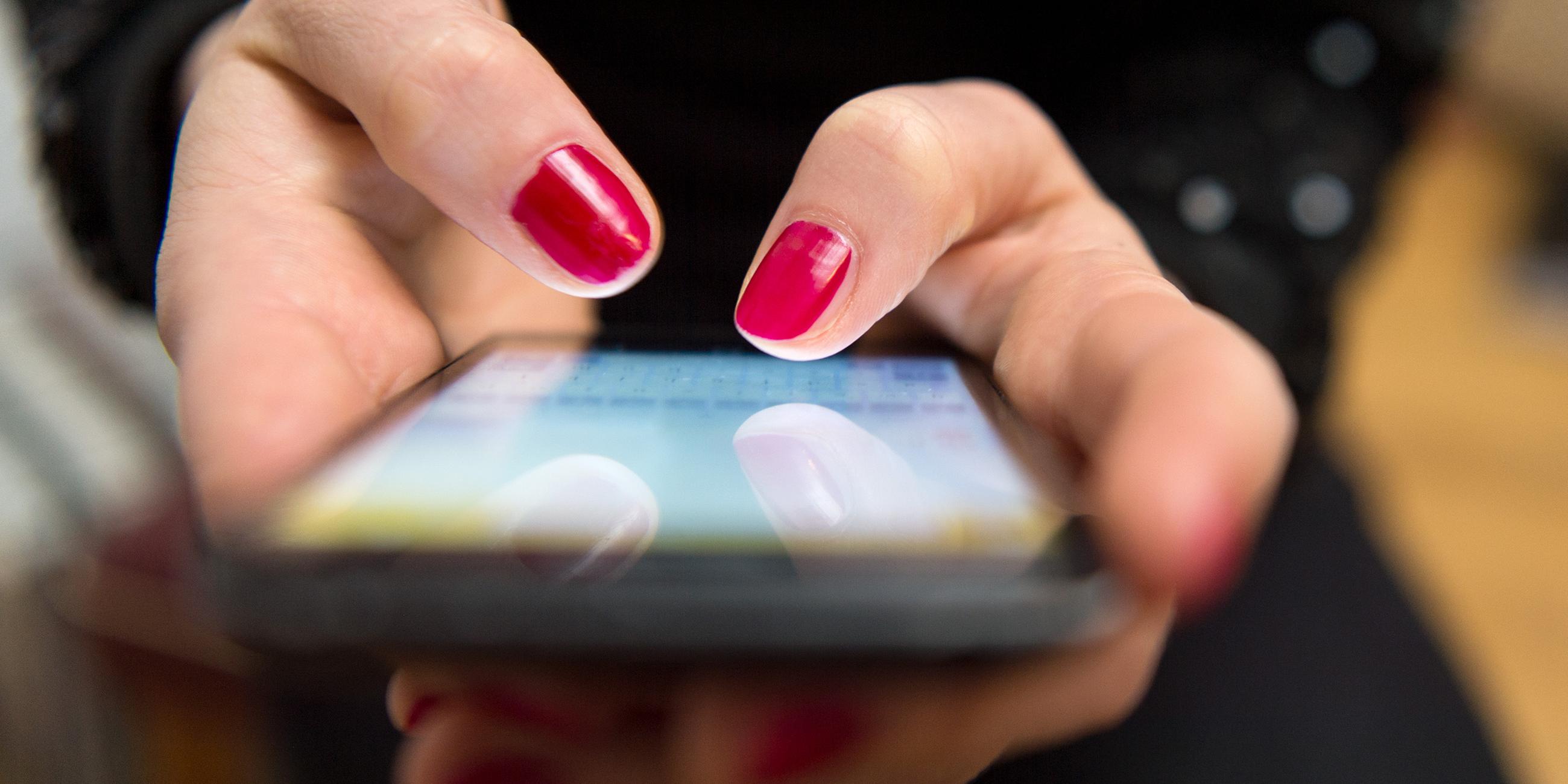 Eine Frau tippt auf einem Smartphone.