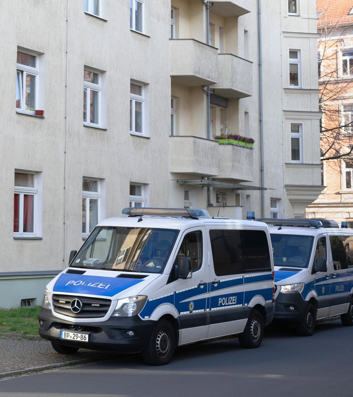 Einsatzfahrzeuge der Polizei stehen während einer Razzia gegen mutmaßliche Rechtsextreme im Dresdner Stadtteil Cotta vor einem Wohnhaus.