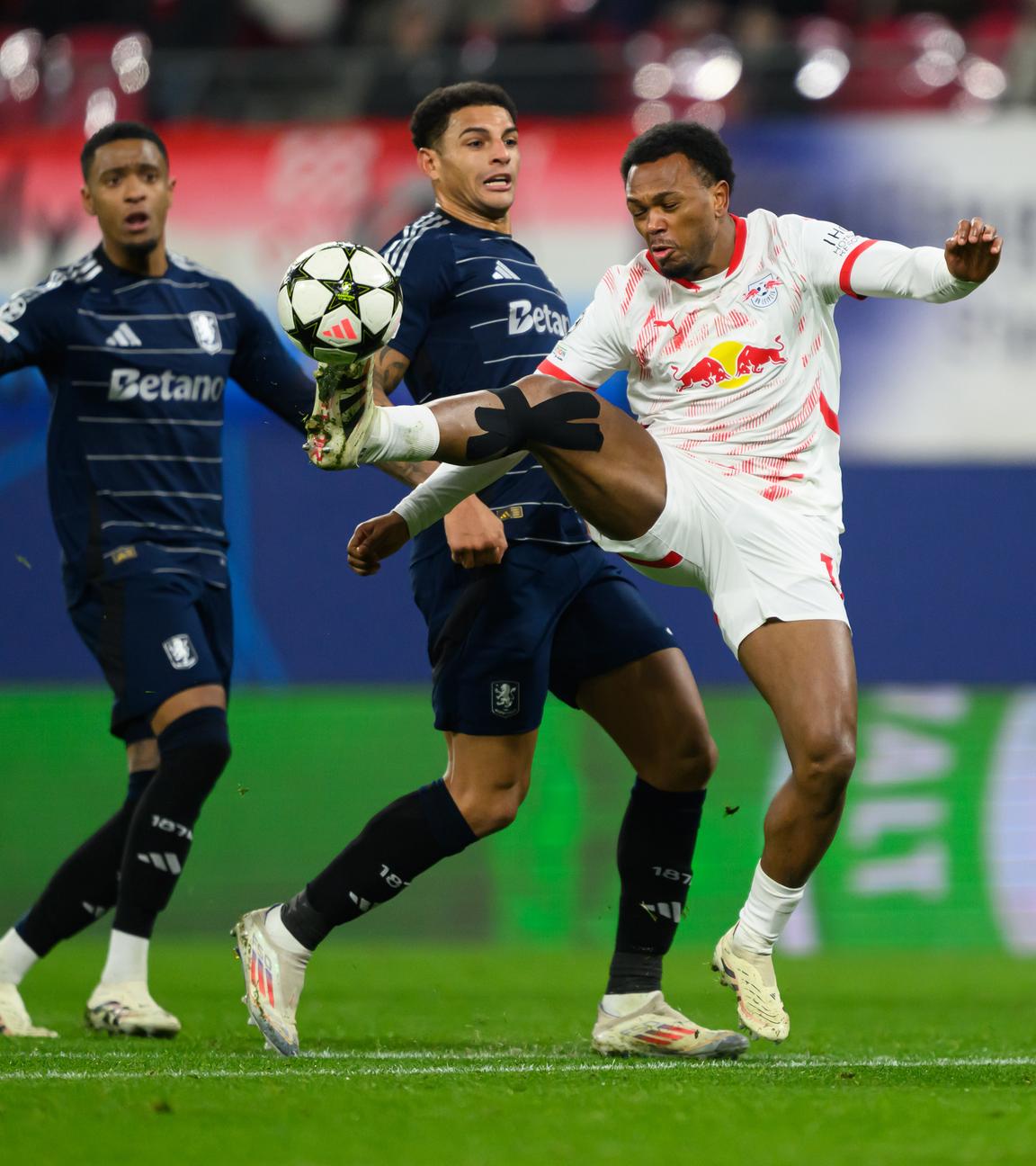 Fußball-Champions League, RB Leipzig - Aston Villa: Lois Openda (3.v.l.) staubt gegen Ezri Konsa (l.), Diego Carlos (2.v.l.) und Torwart Emiliano Martinez ab und macht sich auf den Weg, das Tor zum 1:1 zu erzielen.