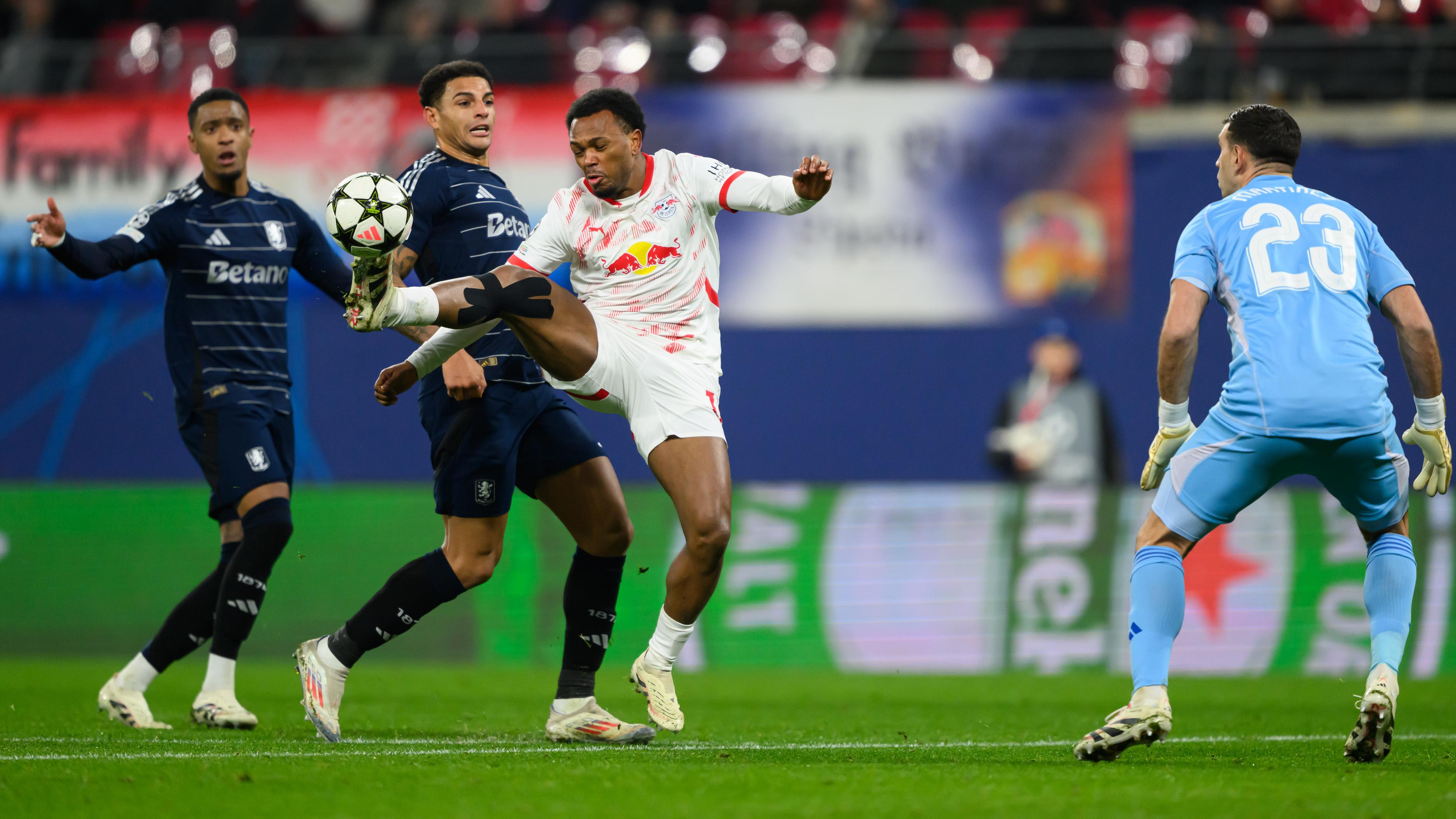 Fußball-Champions League, RB Leipzig - Aston Villa: Lois Openda (3.v.l.) staubt gegen Ezri Konsa (l.), Diego Carlos (2.v.l.) und Torwart Emiliano Martinez ab und macht sich auf den Weg, das Tor zum 1:1 zu erzielen.