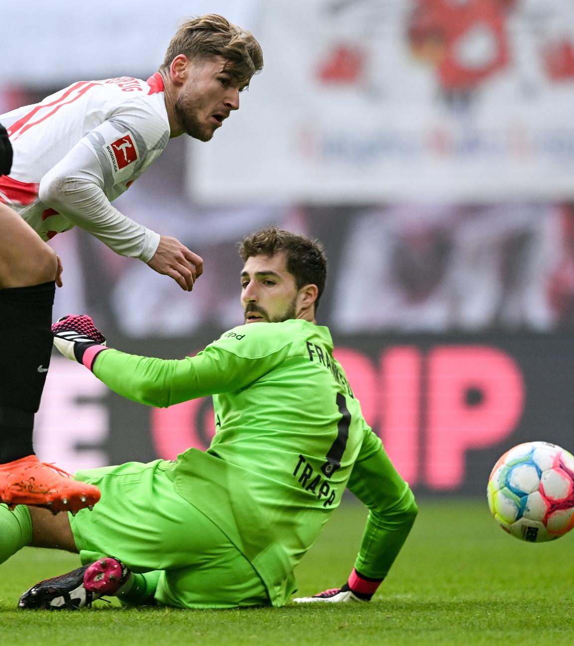 Der Leipziger Timo Werner erzielt beim Bundesliga-Fußballspiel zwischen RB Leipzig und Eintracht Frankfurt neben Frankfurts Makoto Hasebe (L) und Frankfurts Torhüter Kevin Trapp den Führungstreffer, 25.02.2023, in Leipzig