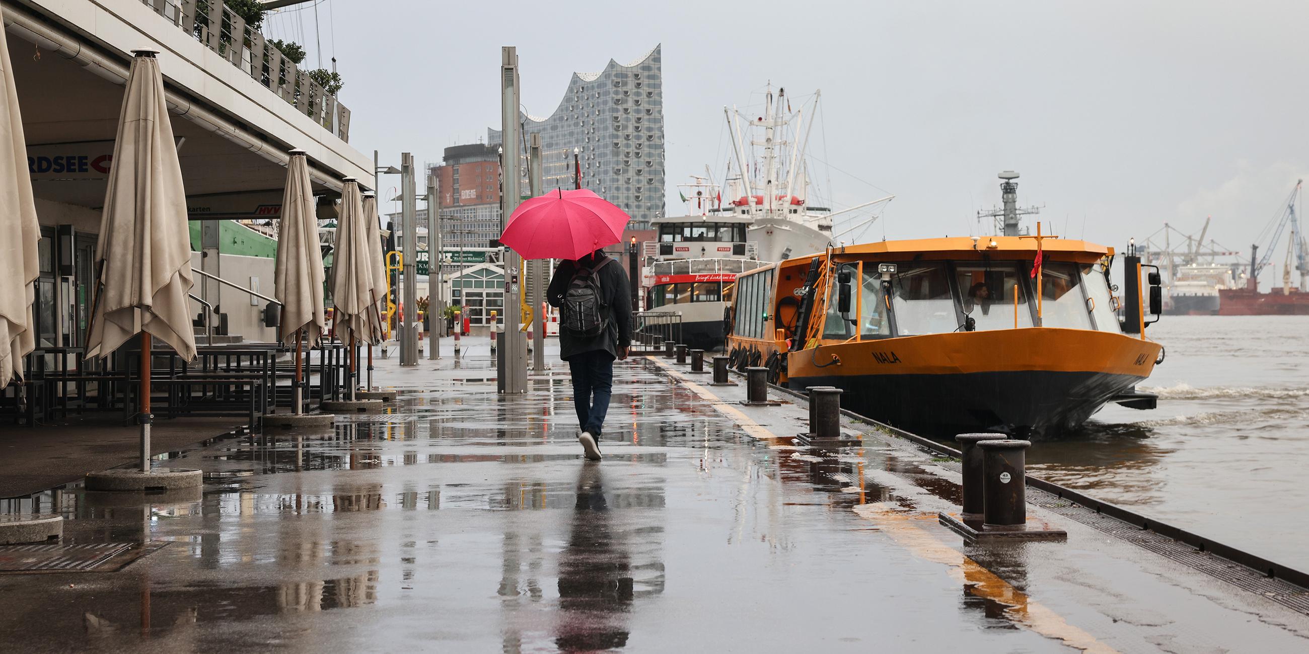 Ein Passant mit Regenschirm an den Landungsbrücken in Hamburg