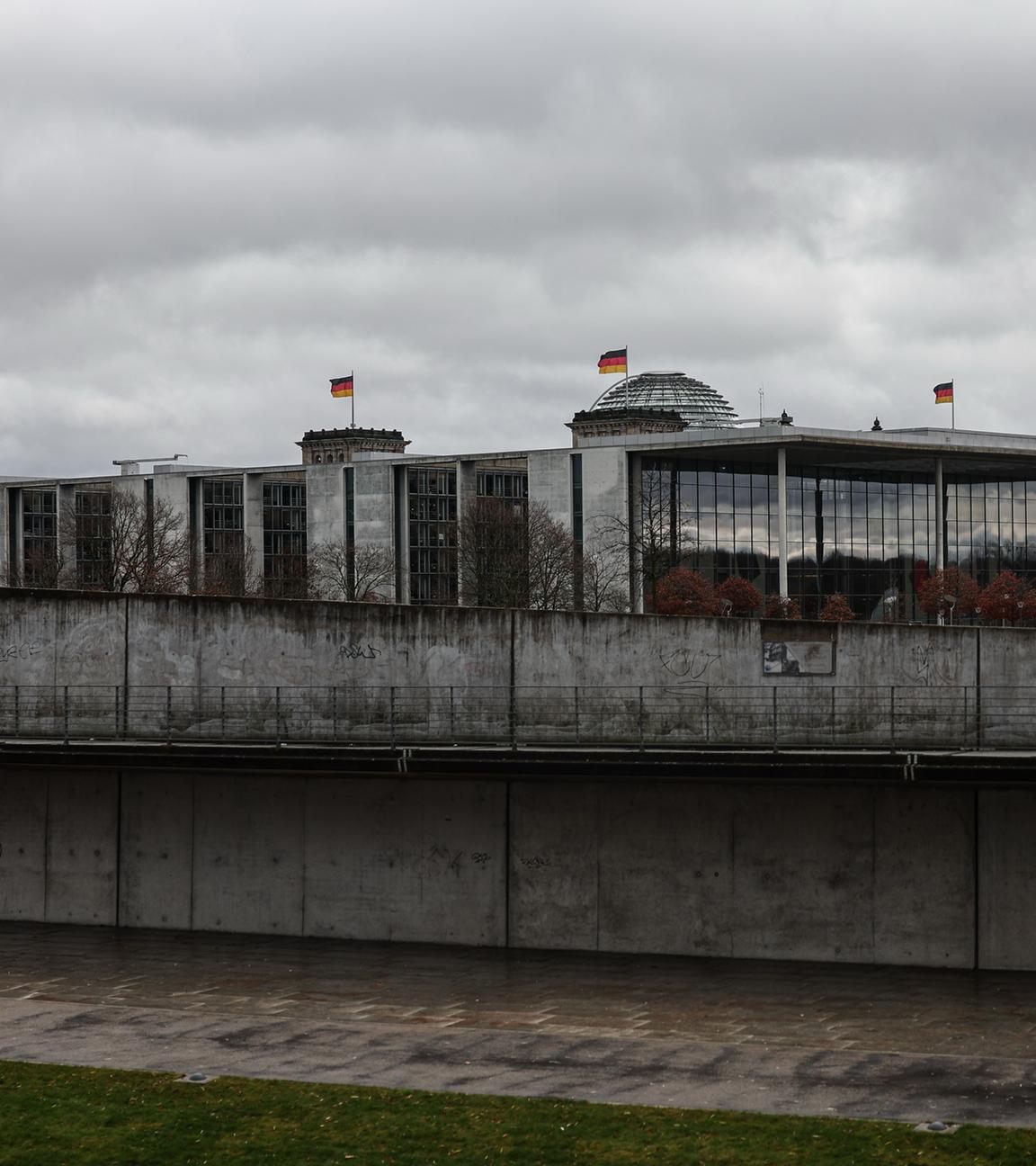 Berlin: Blick auf das Paul-Löbe-Haus und die Kuppel des Reichstagsgebäudes mit wehenden Deutschlandflaggen.