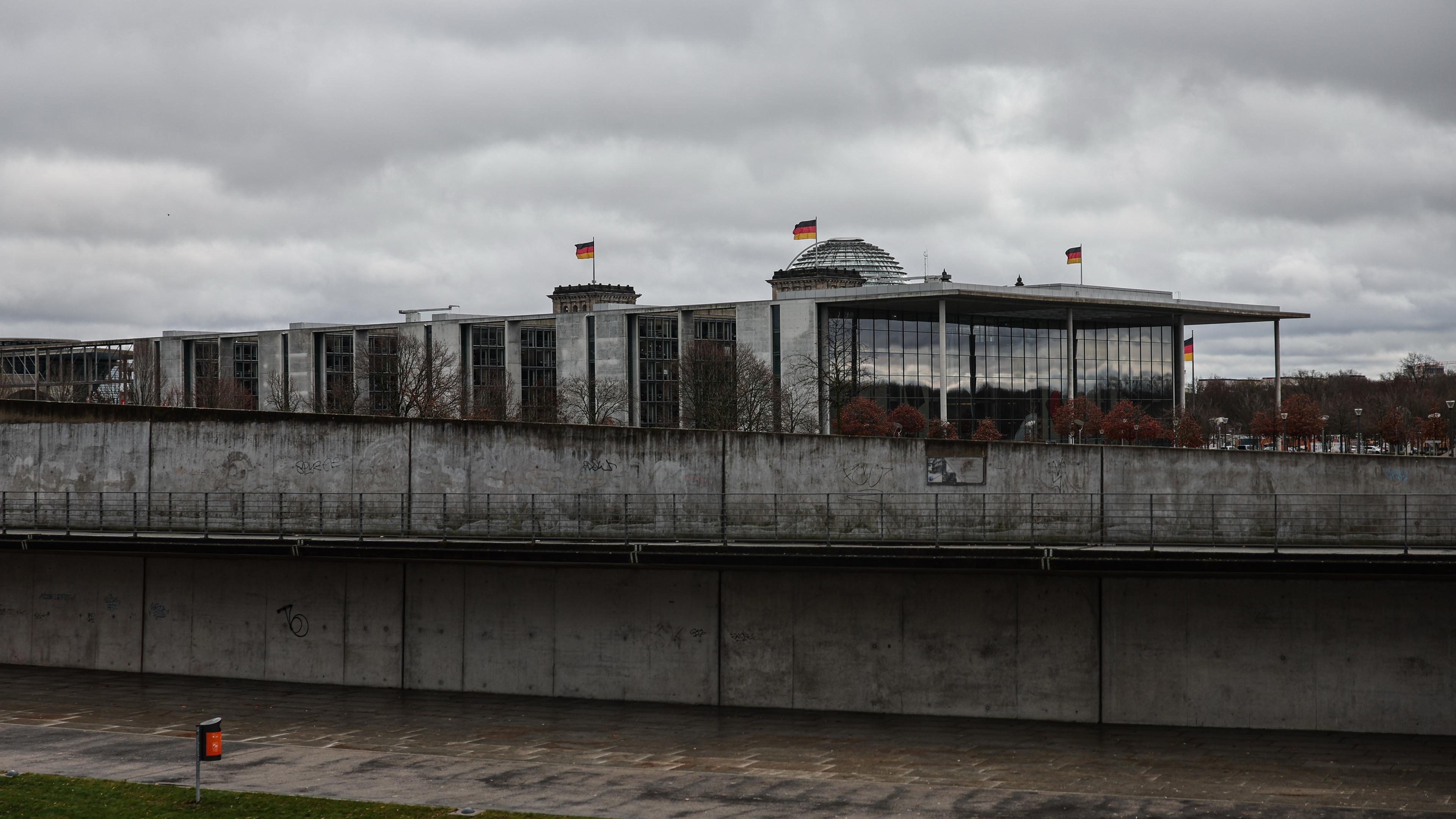 Berlin: Blick auf das Paul-Löbe-Haus und die Kuppel des Reichstagsgebäudes mit wehenden Deutschlandflaggen.