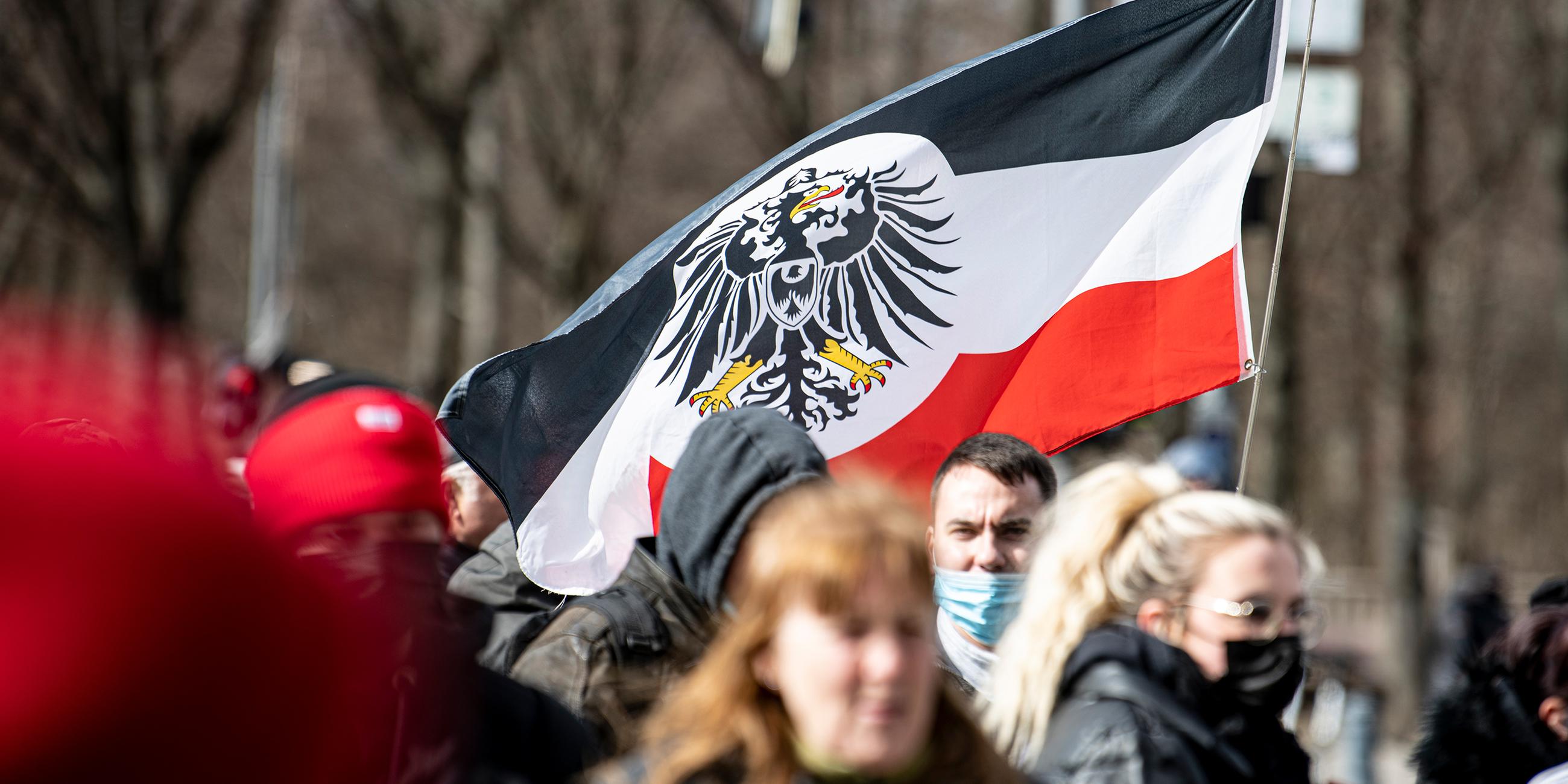 Berlin: Teilnehmer einer Demonstration von Rechtsextremisten und sogenannten Reichsbürgern laufen mit einer Flagge aus dem Kaiserreich die Straße des 17. Juni entlang.