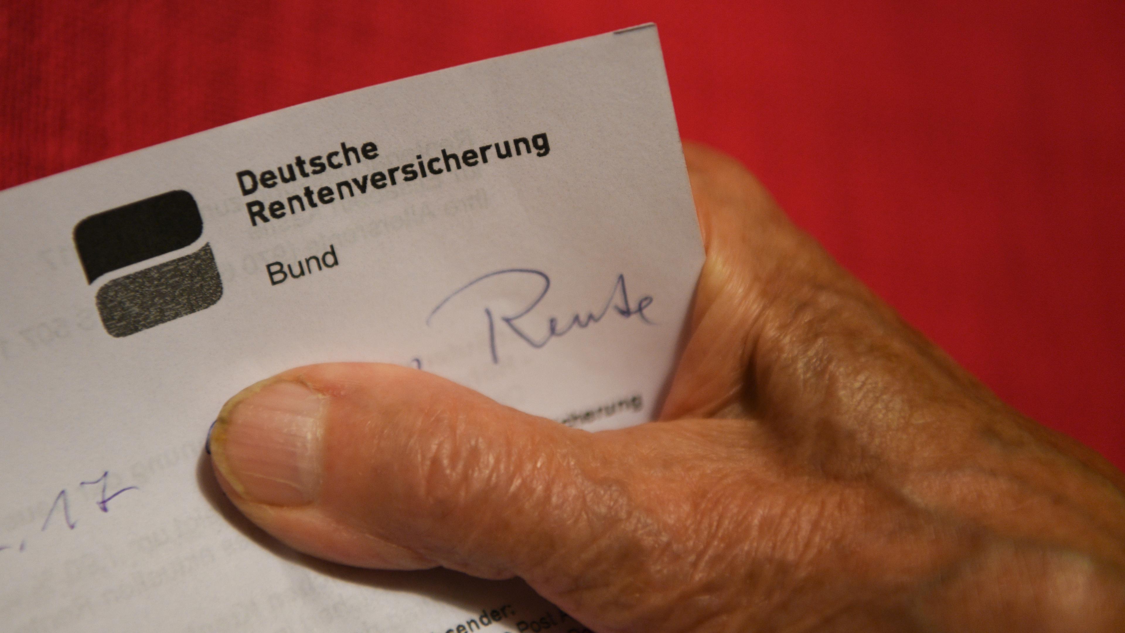 Eine Rentnerin hält ihren Rentenbescheid in der Hand.