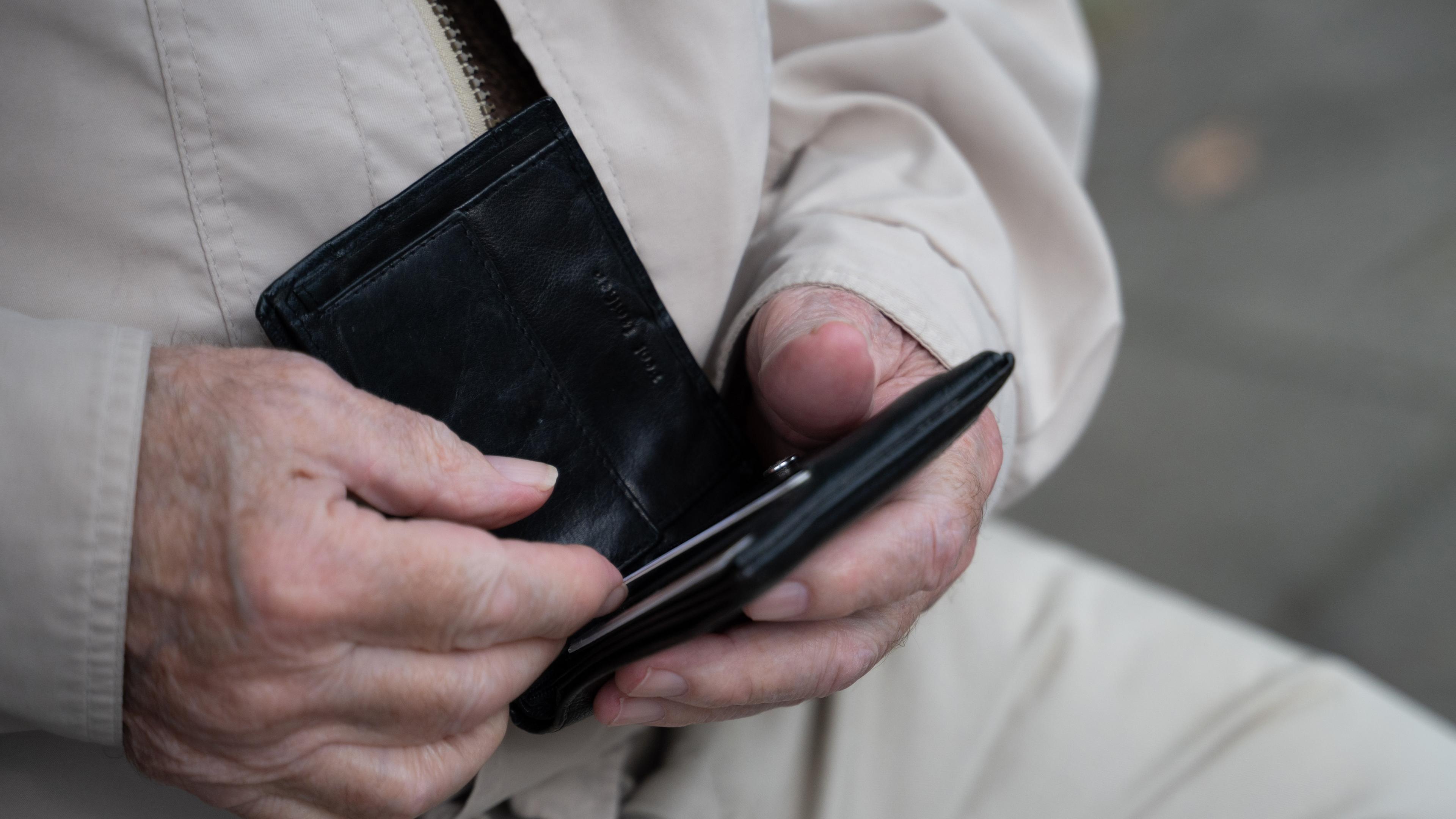 Ein Rentner hält sein Portemonnaie in der Hand.