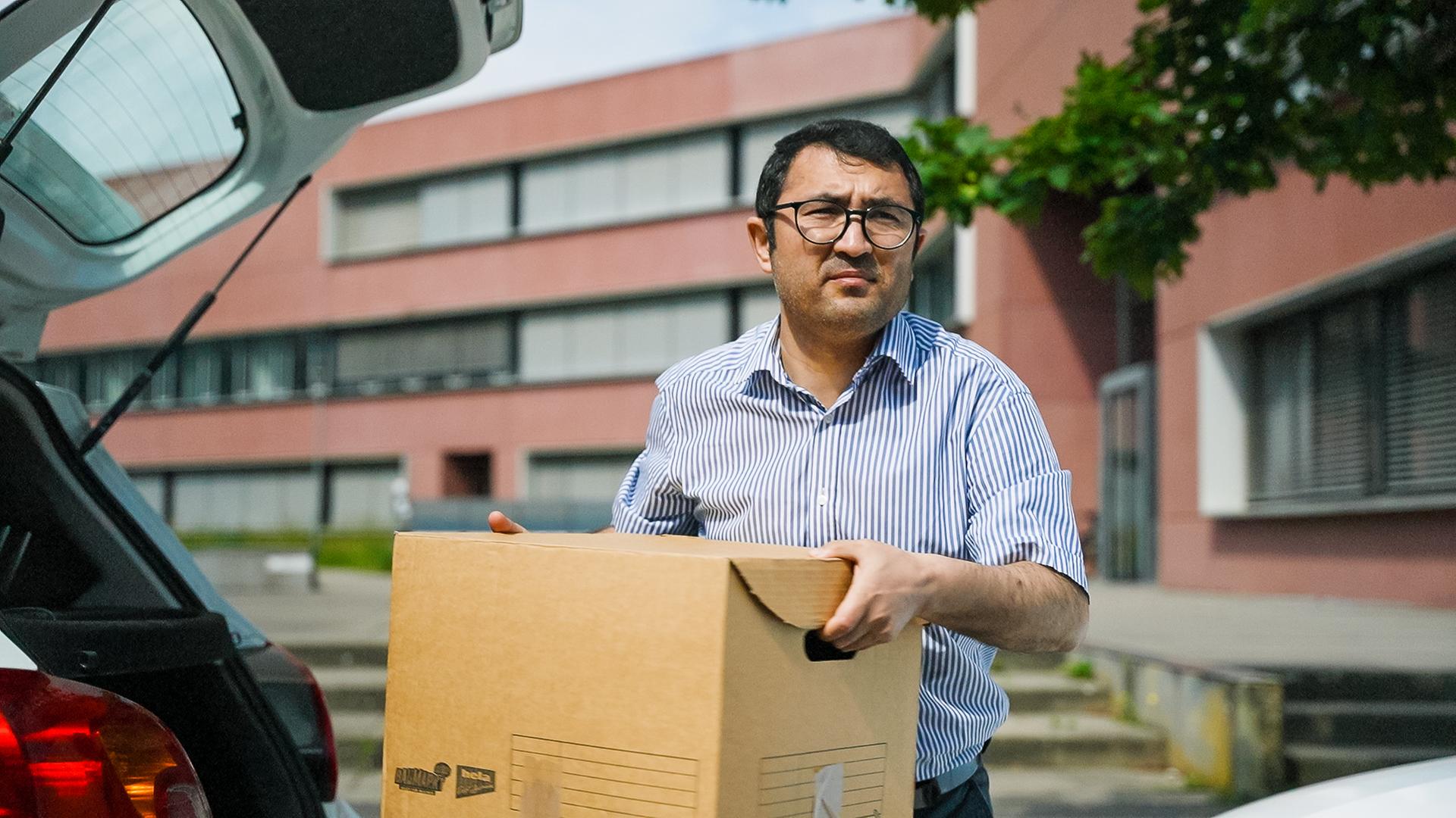 Reza Haidari trägt eine Kiste beim Einzug in sein eigenes Büro.