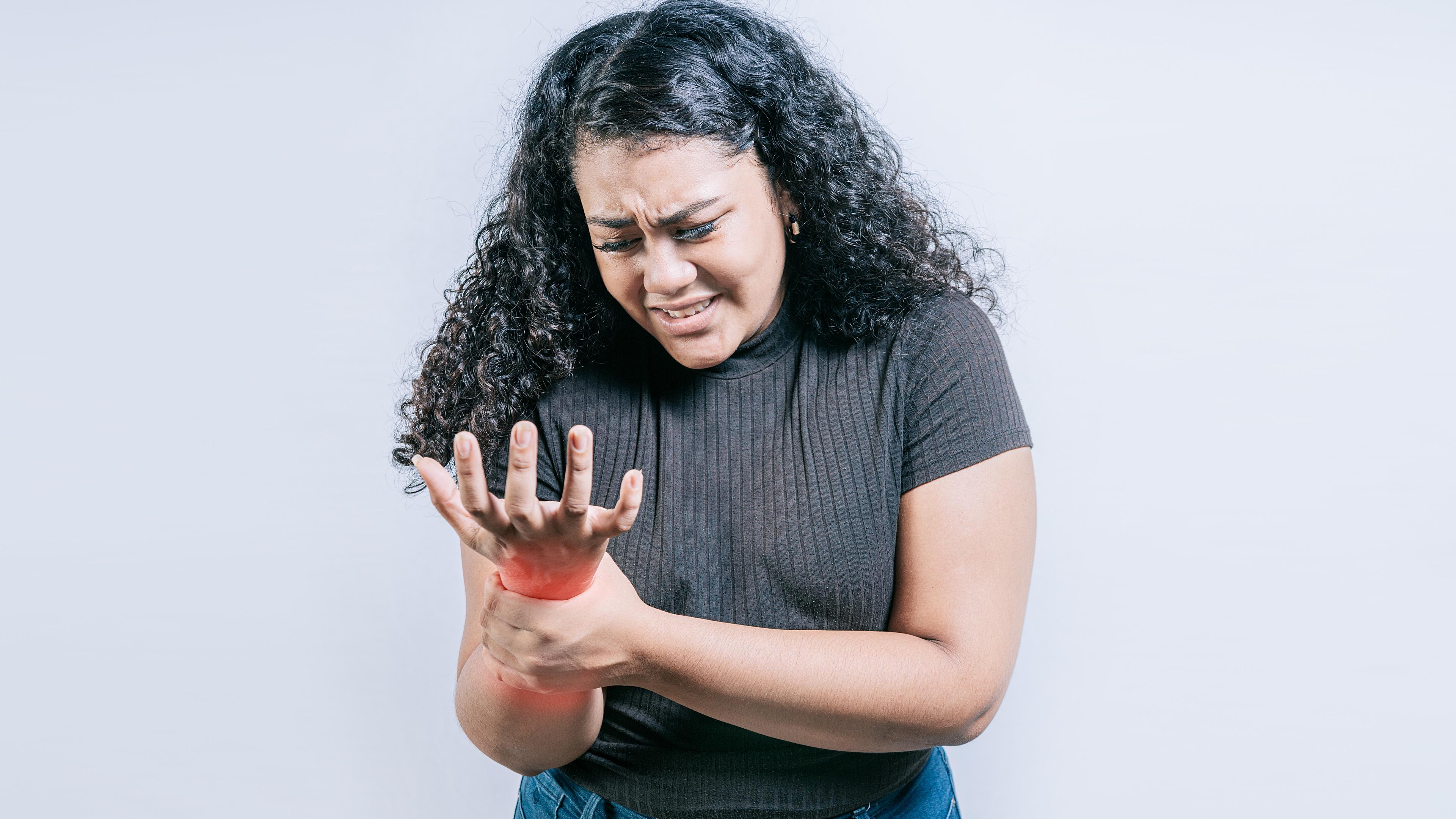 Eine junge Frau hält sich das schmerzende Handgelenk.