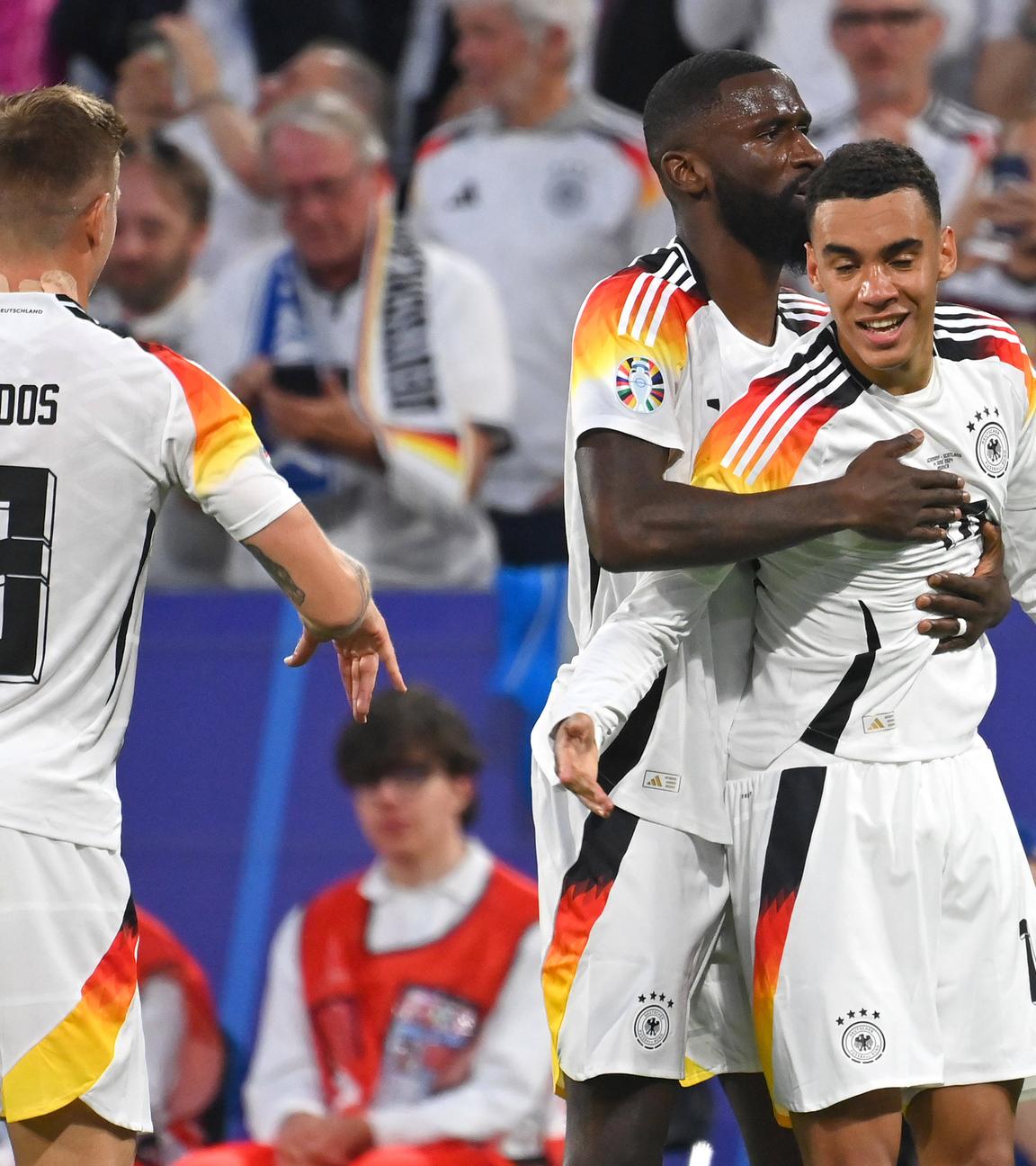 EM-Eröffnungsspiel Deutschland - Schottland am 14.6.2024 in München: Antonio Rüdiger gratuliert Jamal Musiala (rechts) zu seinem Tor. Links Toni Kroos.