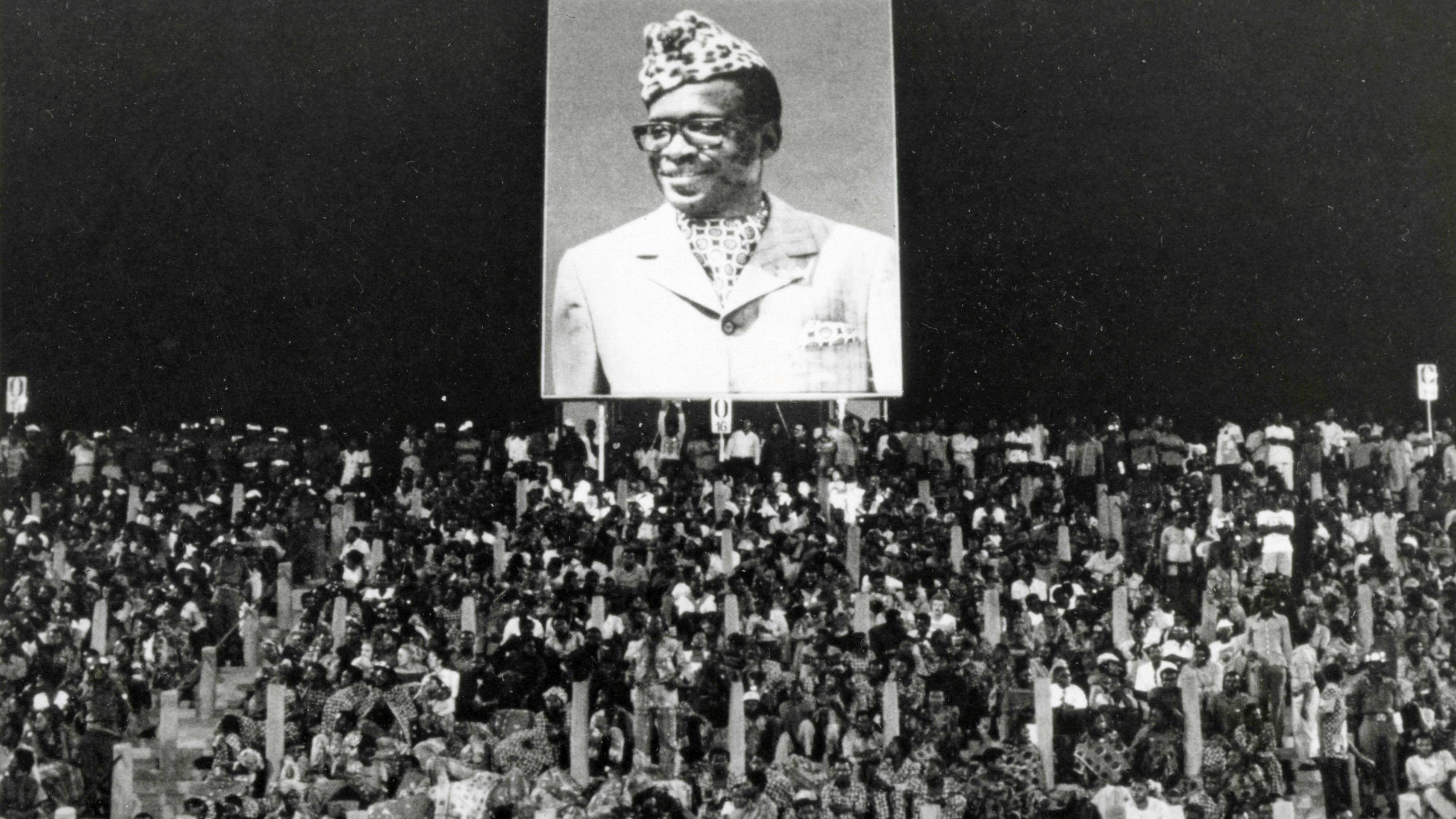 Zuschauer unter einem Plakat von Zaires Präsident Mobutu beim Boxkampft George Foreman - Muhammad Ali am 30. Oktober 1974 in Kinshasa