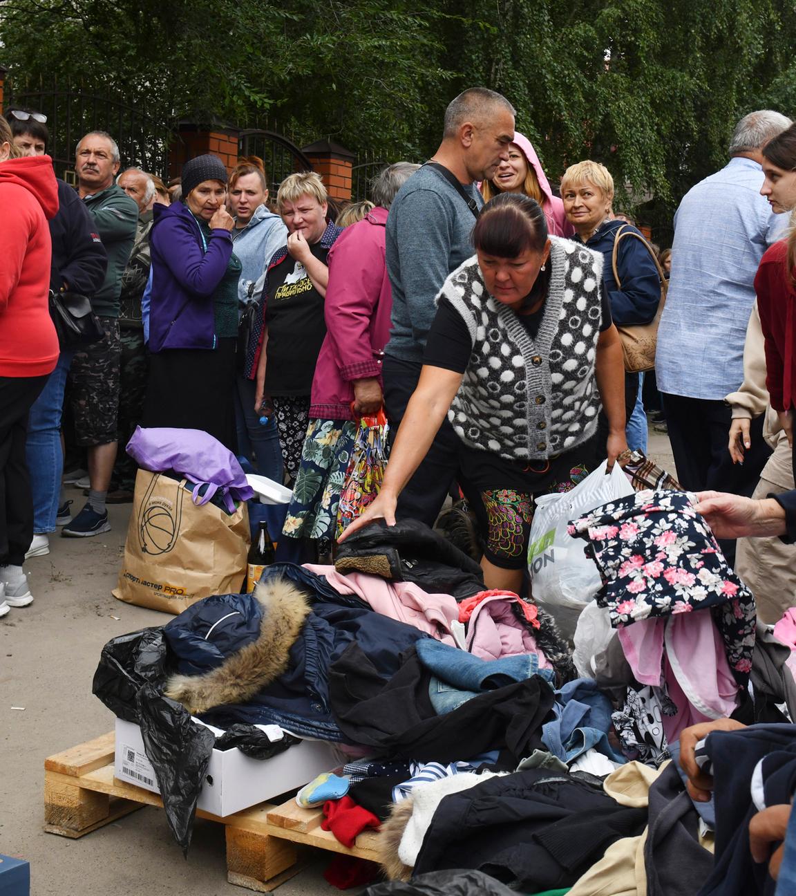 12.08.2024, Russland, Kursk: Menschen, die vor den Kämpfen zwischen russischen und ukrainischen Streitkräften evakuiert wurden, warten in einem Verteilungszentrum auf humanitäre Hilfe.