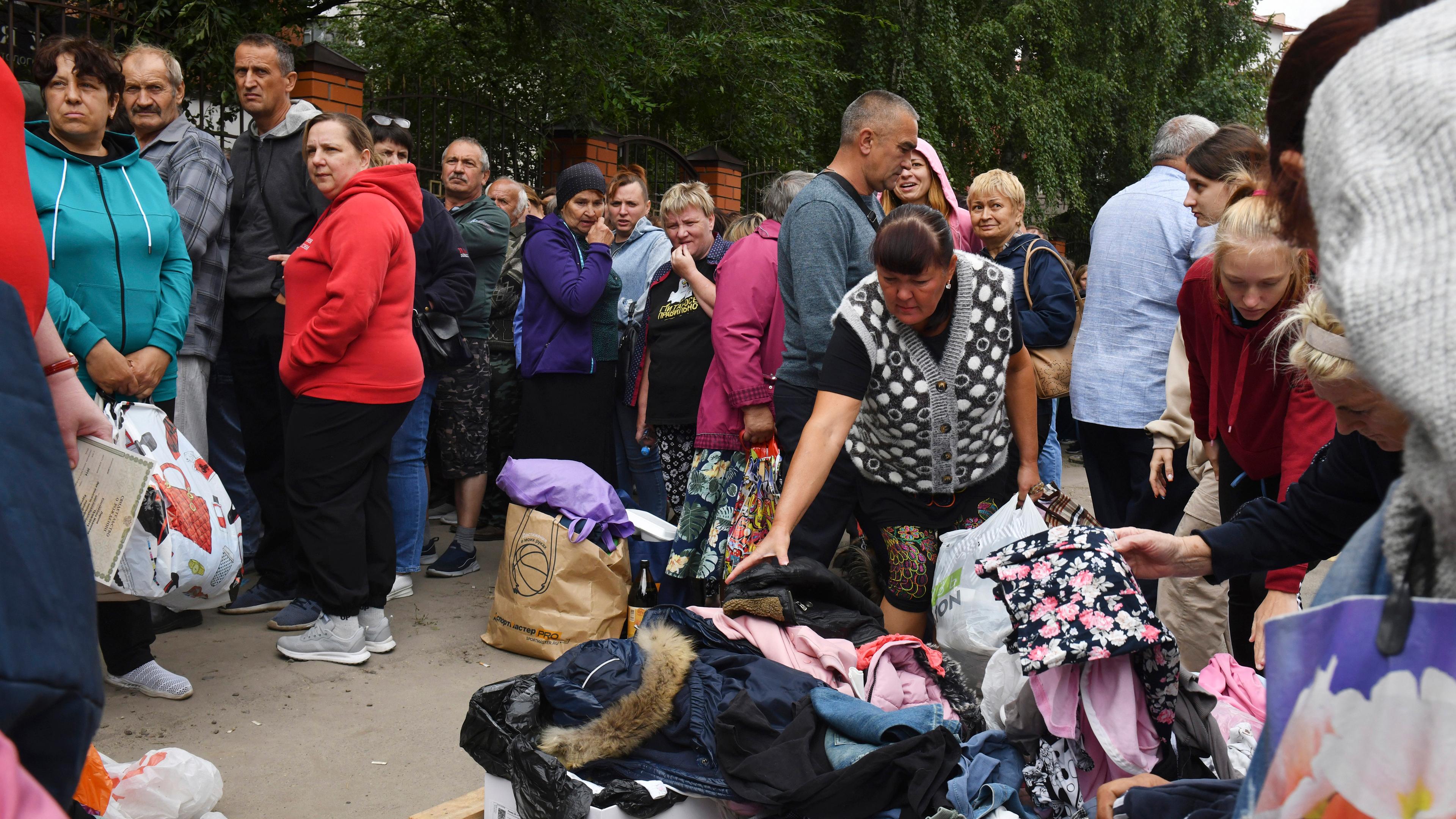 12.08.2024, Russland, Kursk: Menschen, die vor den Kämpfen zwischen russischen und ukrainischen Streitkräften evakuiert wurden, warten in einem Verteilungszentrum auf humanitäre Hilfe.