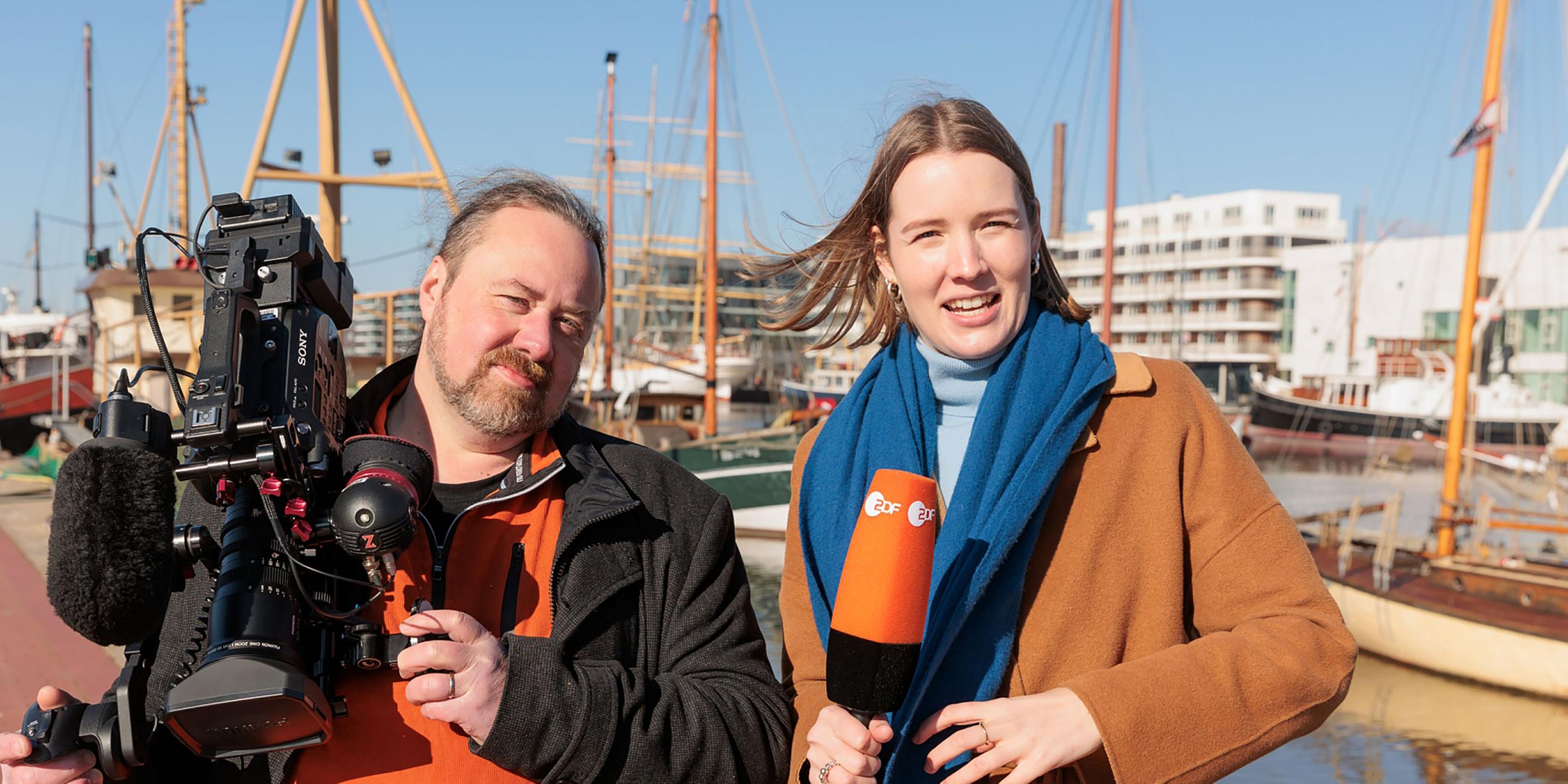 ZDF-Reporterin Ruth de Carné und Kameramann und Cutter Thomas Henke stehen an einem Deich in Bremerhaven.