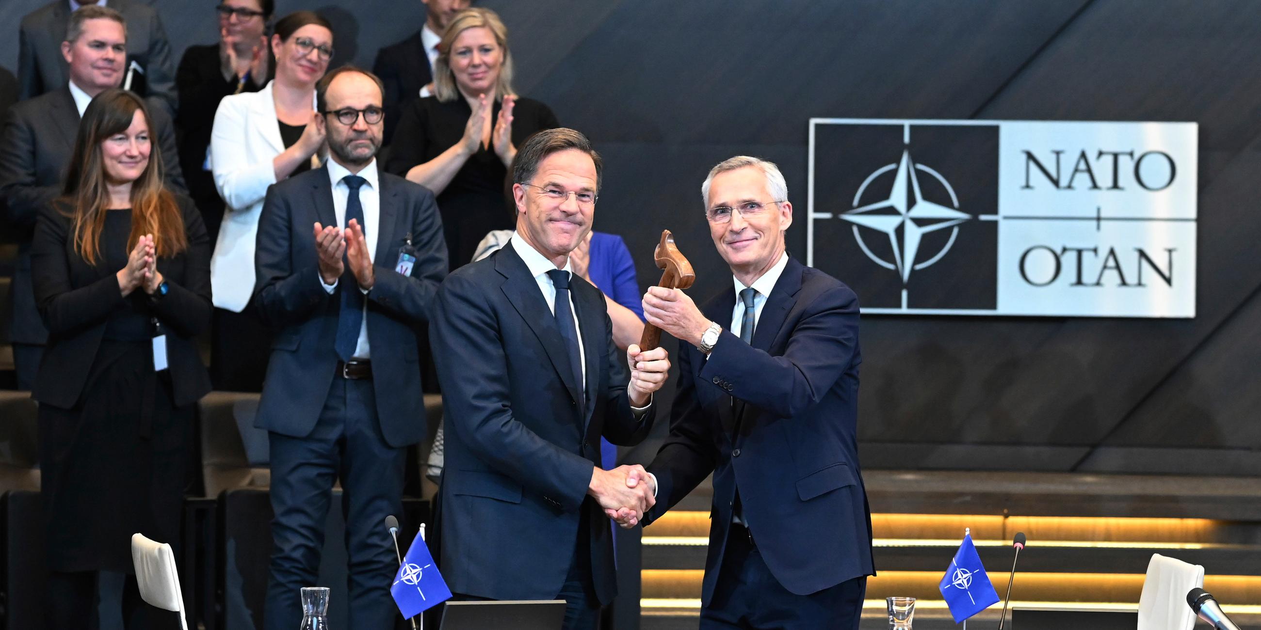 01.10.2024, Belgien, Brüssel: Der scheidende NATO-Generalsekretär Jens Stoltenberg (r) steht neben dem neuen NATO-Generalsekretär Mark Rutte bei der Amtsübergabe im NATO-Hauptquartier.