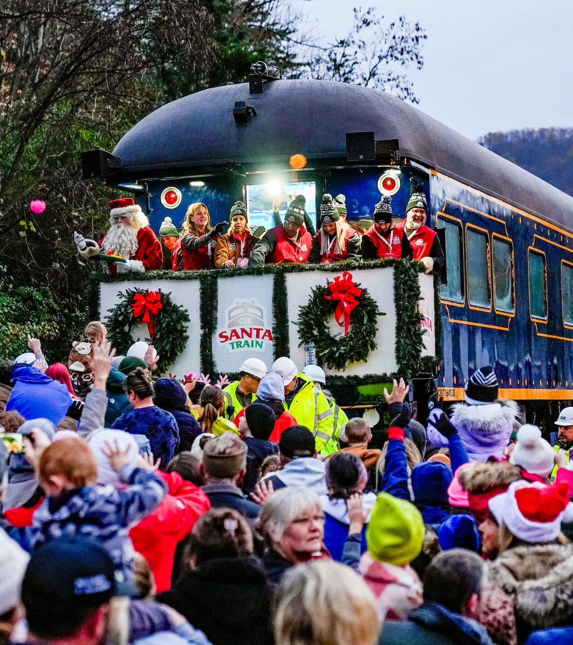 eine Menschenmenge steht vor dem weihnachtlich geschmückten Santa Train