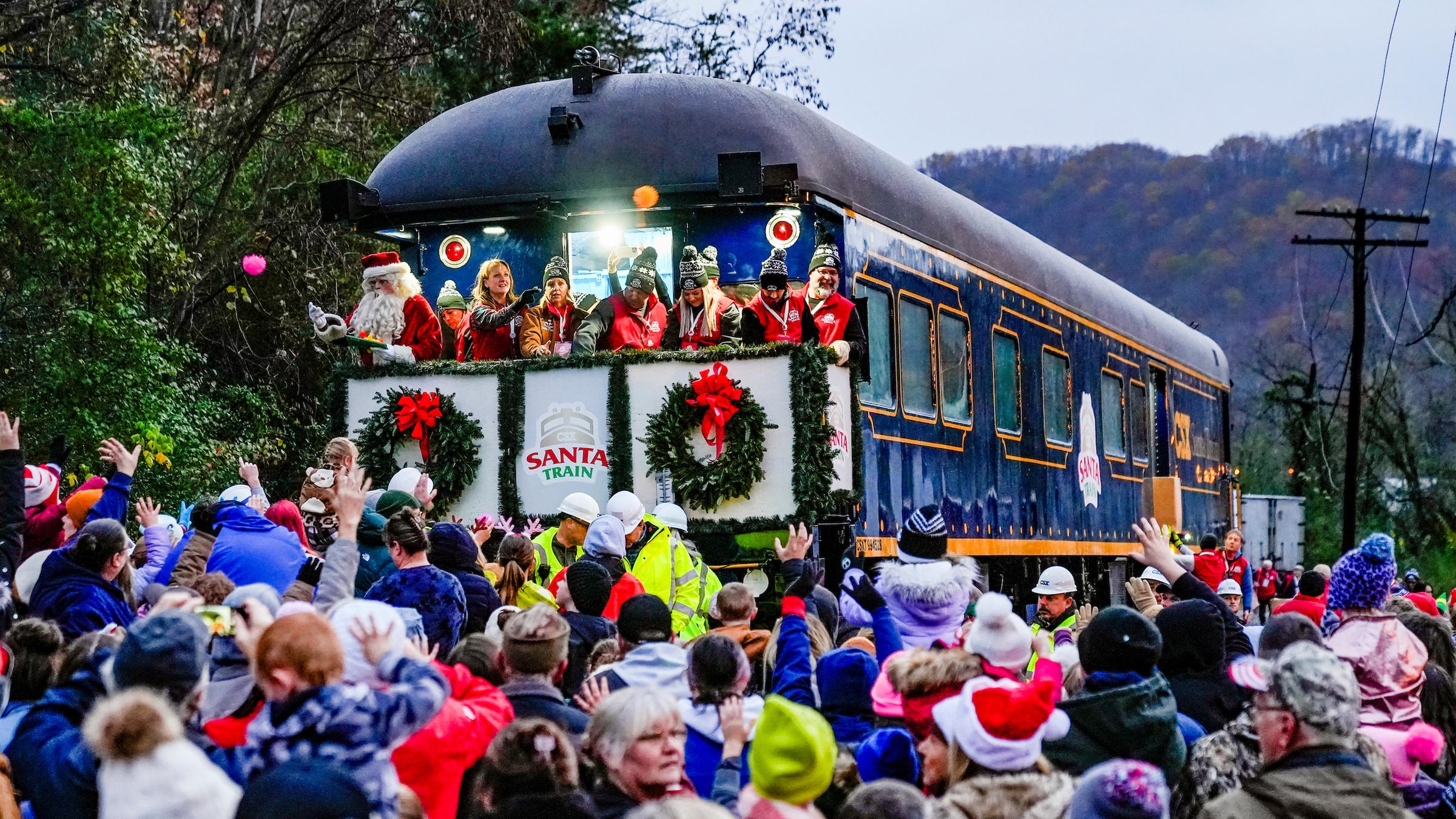 eine Menschenmenge steht vor dem weihnachtlich geschmückten Santa Train