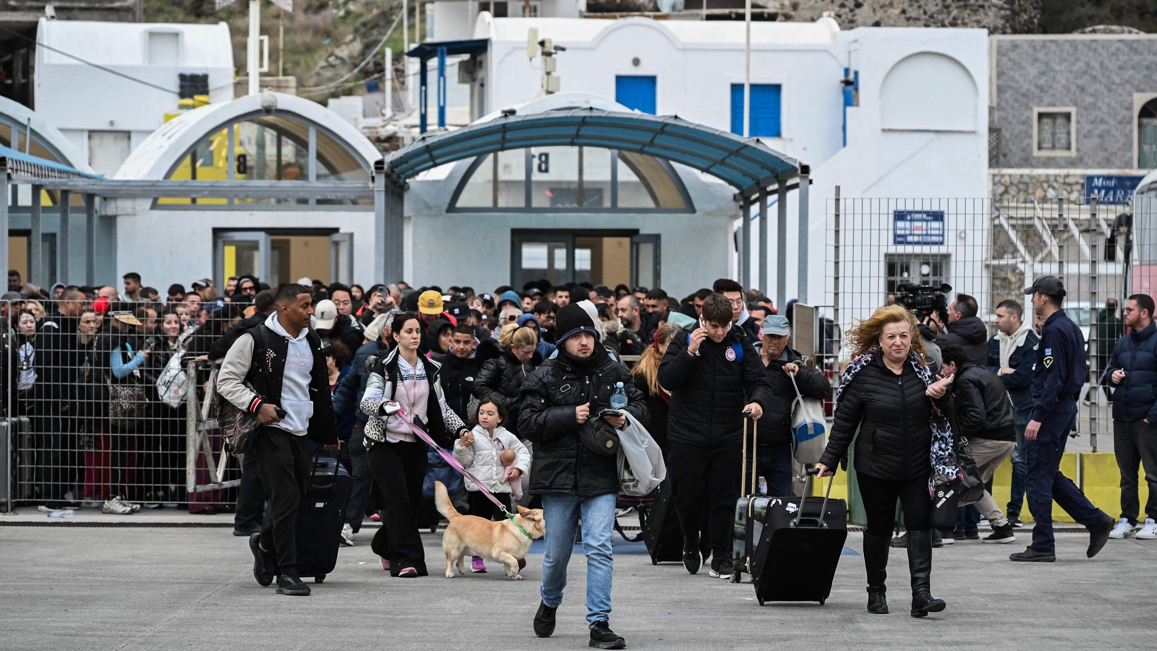 People walk on the platform to embark a ferry as they prepare to leave in the wake of recurring earthquakes, on the Greek Island of Santorini 