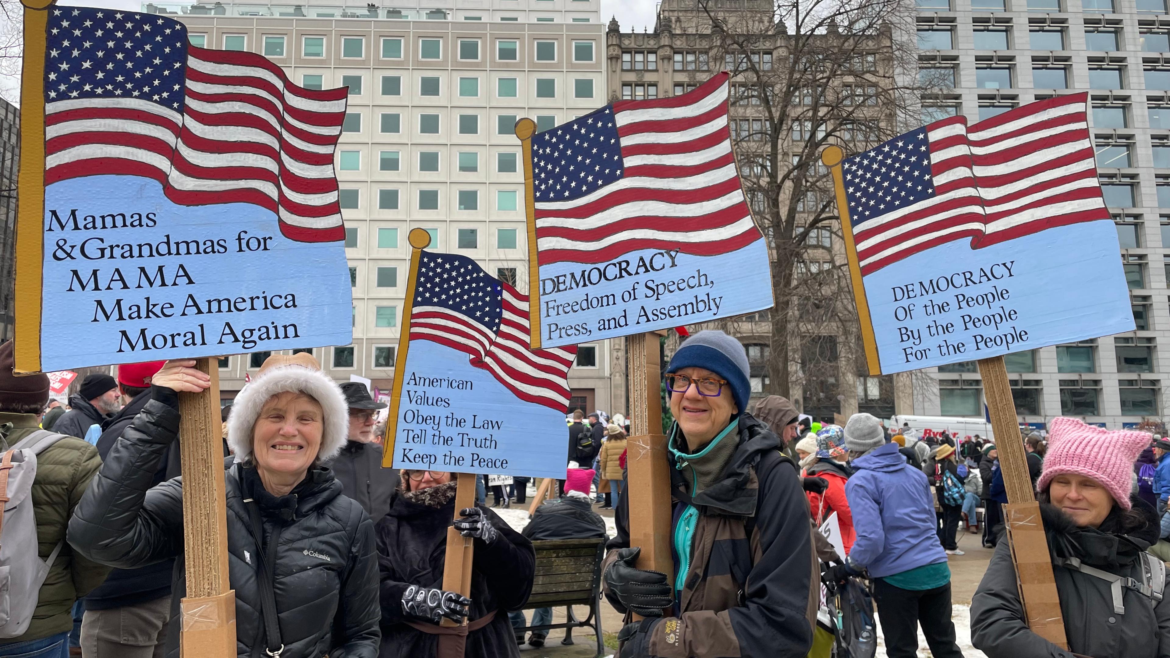 Eine Gruppe von vier Personen hält gebastelte US-Flaggen in der Hand auf denen beispielsweise steht: Mach Amerika wieder moralisch.