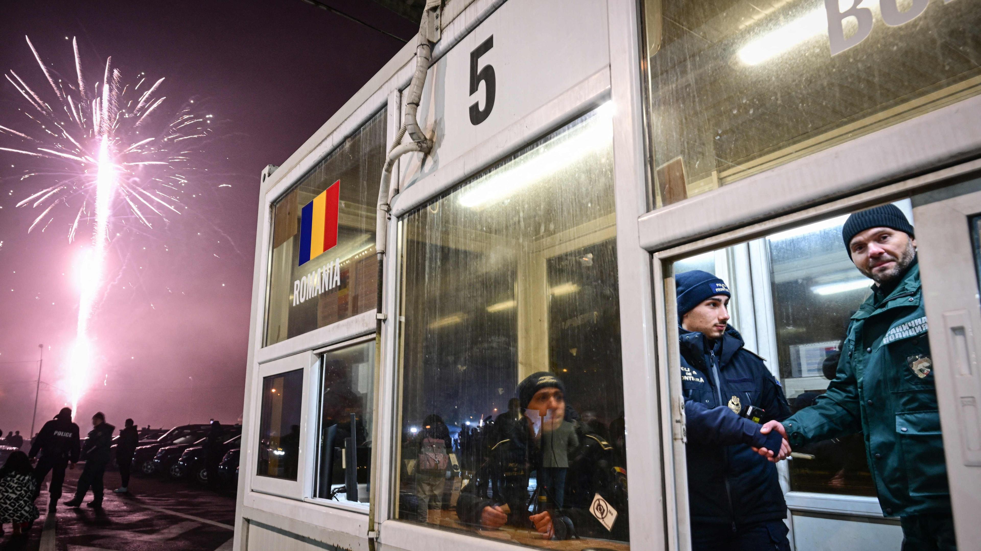 Ein rumänischer und ein bulgarischer Polizeibeamter schütteln sich die Hand an der Grenze der beiden Länder, die jetzt zum Schengen-Raum gehören.