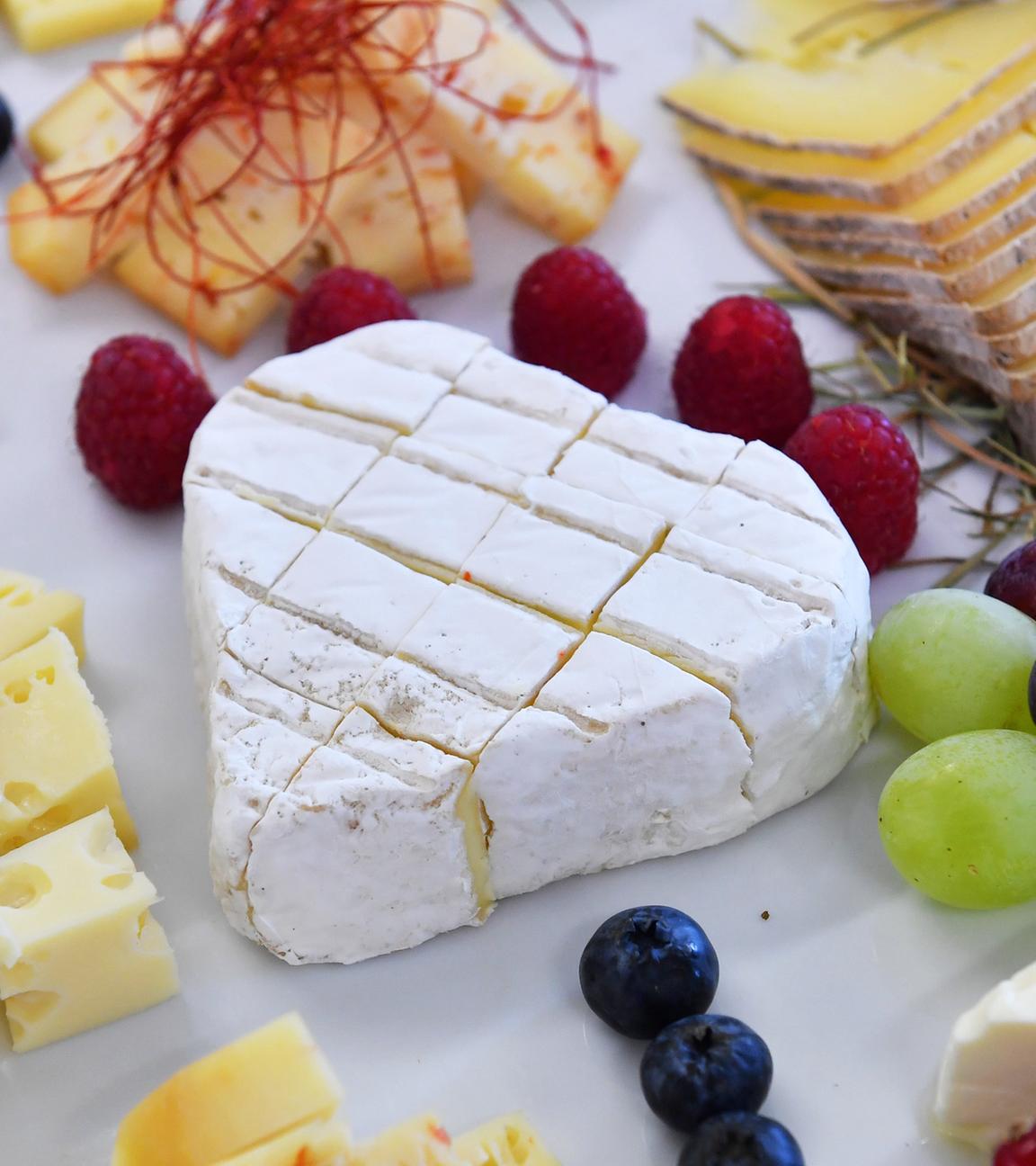 Eine Käseplatte mit Camembert in der Mitte und weiteren Käsesorten außen.