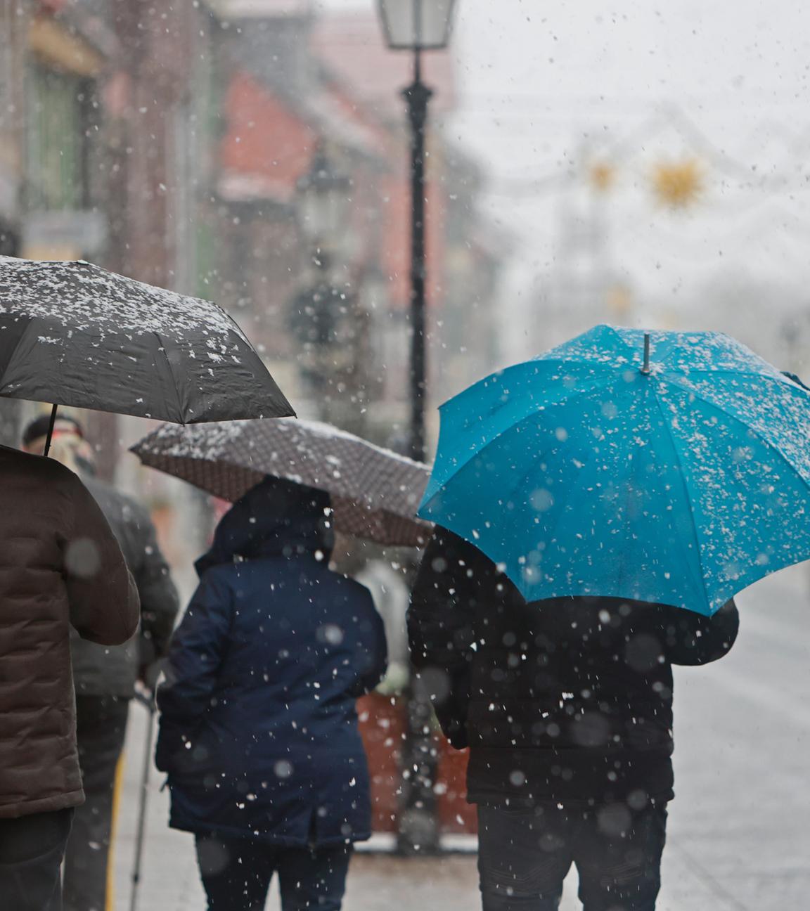 Sachsen-Anhalt, Wernigerode: Menschen gehen mit Regenschirm bei Schneeregen am Montagvormittag durch die Innenstadt von Wernigerode.