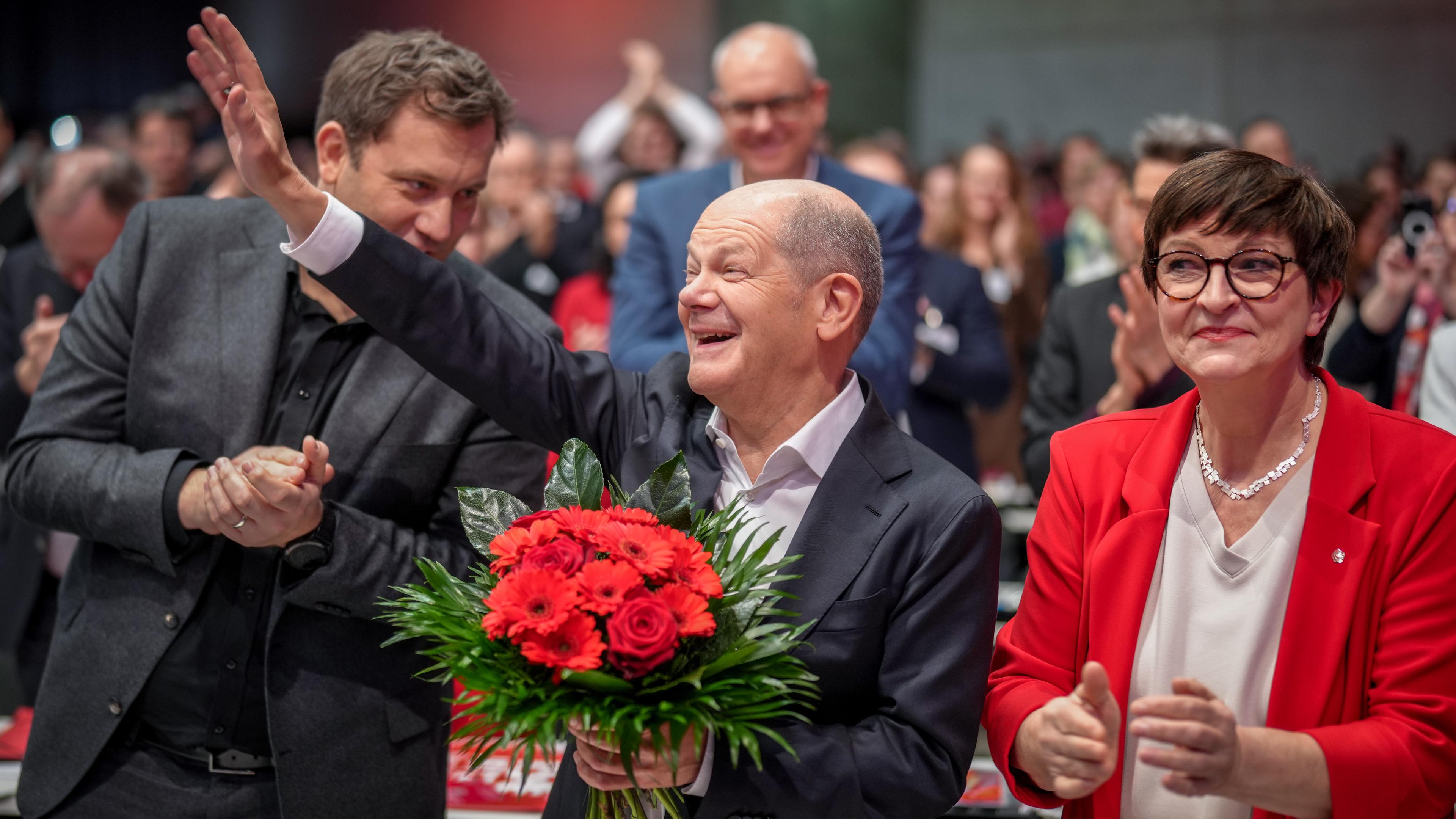 Bundeskanzler Olaf Scholz (SPD, M) winkt nach seiner Wahl zum SPD-Kanzlerkandidaten beim außerordentlichen SPD-Bundesparteitag neben Saskia Esken und Lars Klingbeil, SPD-Bundesvorsitzender. 