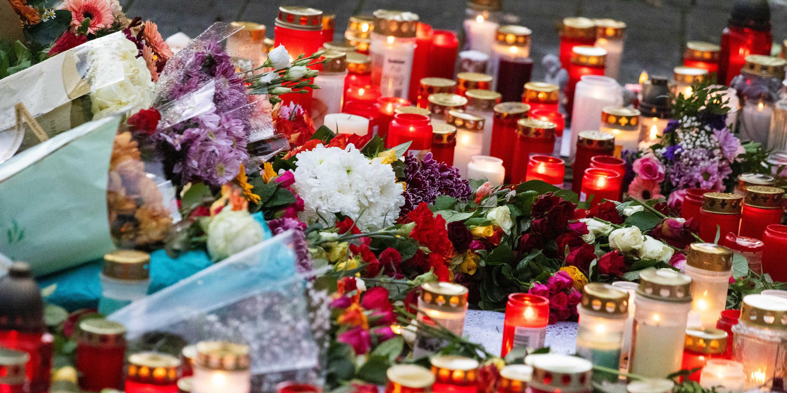 Blumen und Kerzen liegen während einer stillen Gedenkveranstaltung vor einer Schule am 10.11.2023 in Offenburg.