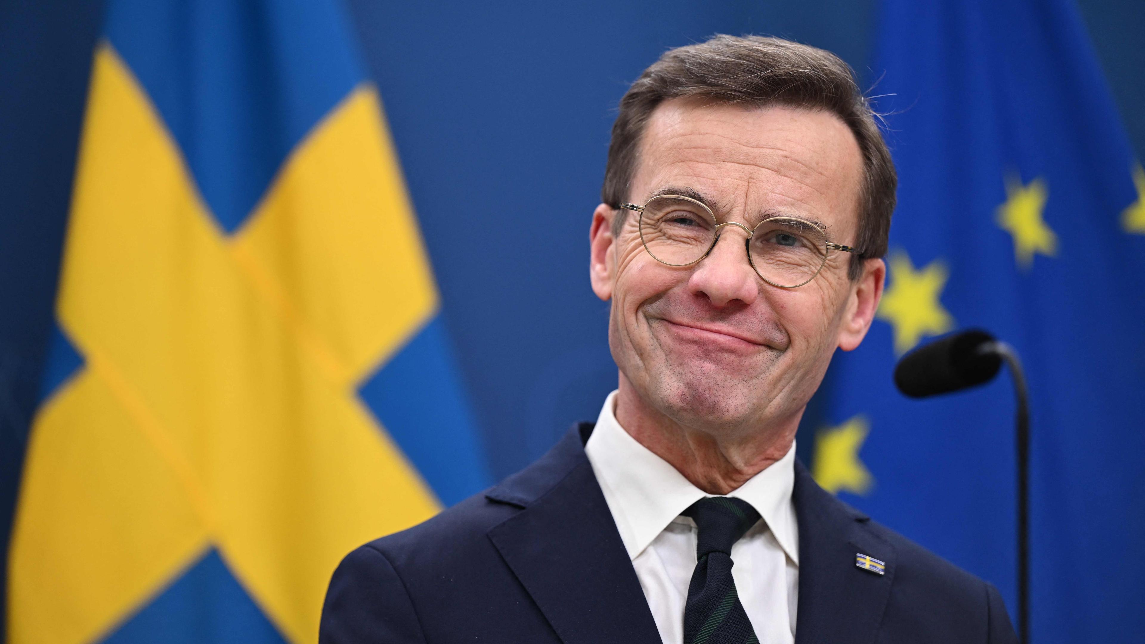 Schwedens Ministerpräsident Kristersson bei einer PK; im Hintergrund Flaggen Schwedens und der EU.