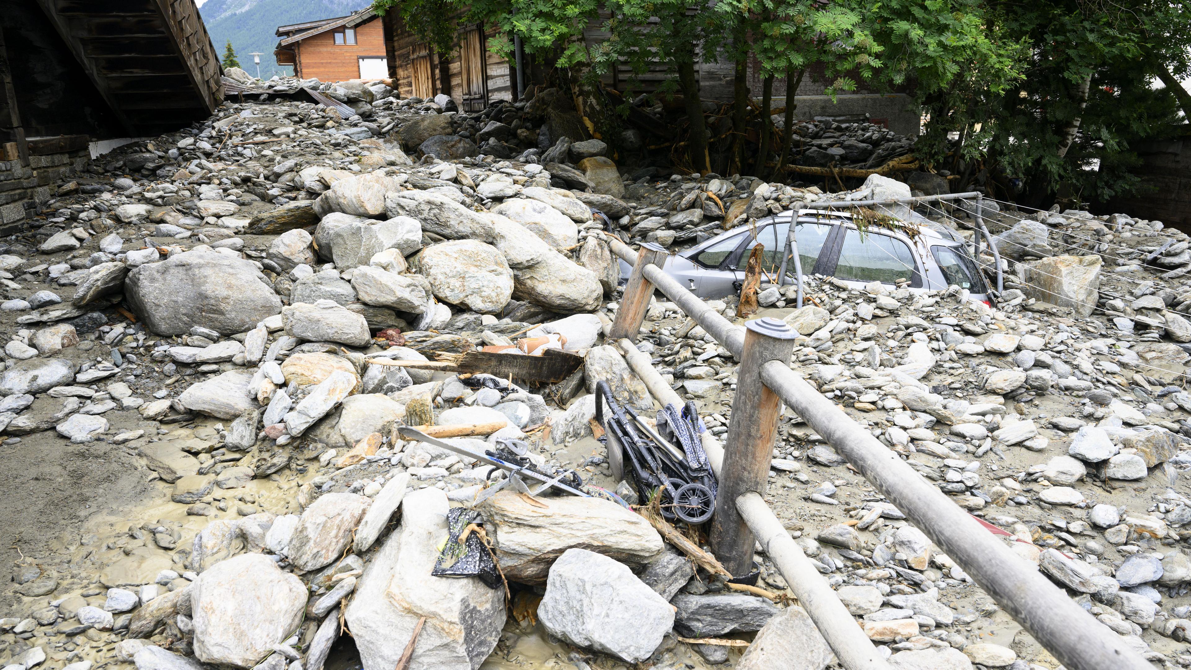 Ein Auto ist teilweise mit Trümmern von einem Erdrutsch bedeckt, nachdem Stürme in Saas-Grund, Schweiz, am 30. Juni 2024 zu schweren Überschwemmungen geführt hatten.