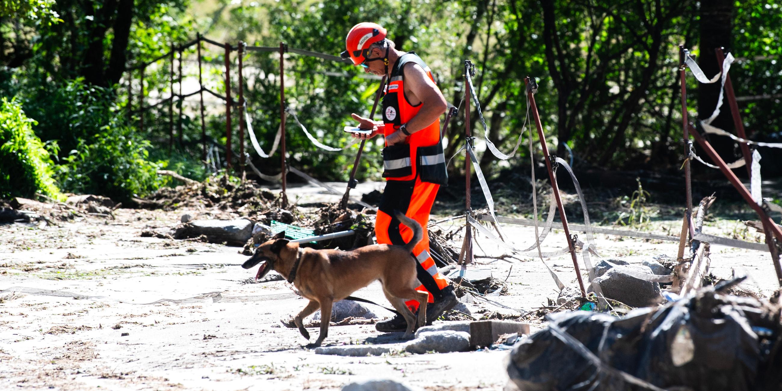 Ein Rettungshelfer geht mit einem Hund während einer Such- und Rettungsaktion an der Stelle eines Erdrutschs spazieren, der durch Unwetter und starken Regen in der Schweiz verursacht wurde.