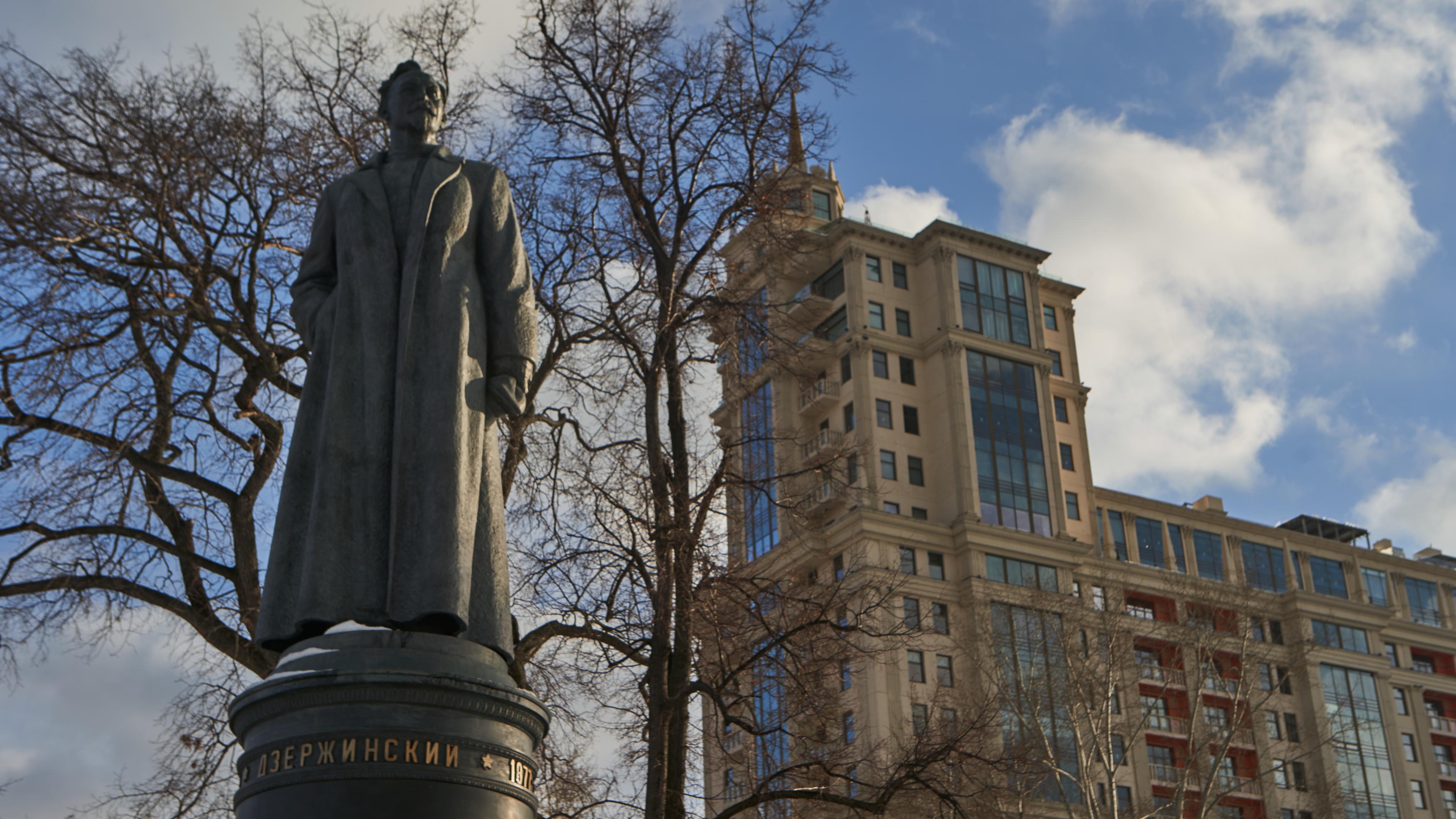 "Schwert und Schild - Russlands Geheimdienste: Tscheka und Roter Terror": Nahaufnahme der Statue von Feliks Dserschinski. Im Hintergrund befinden sich Bäume und ein großes Gebäude.