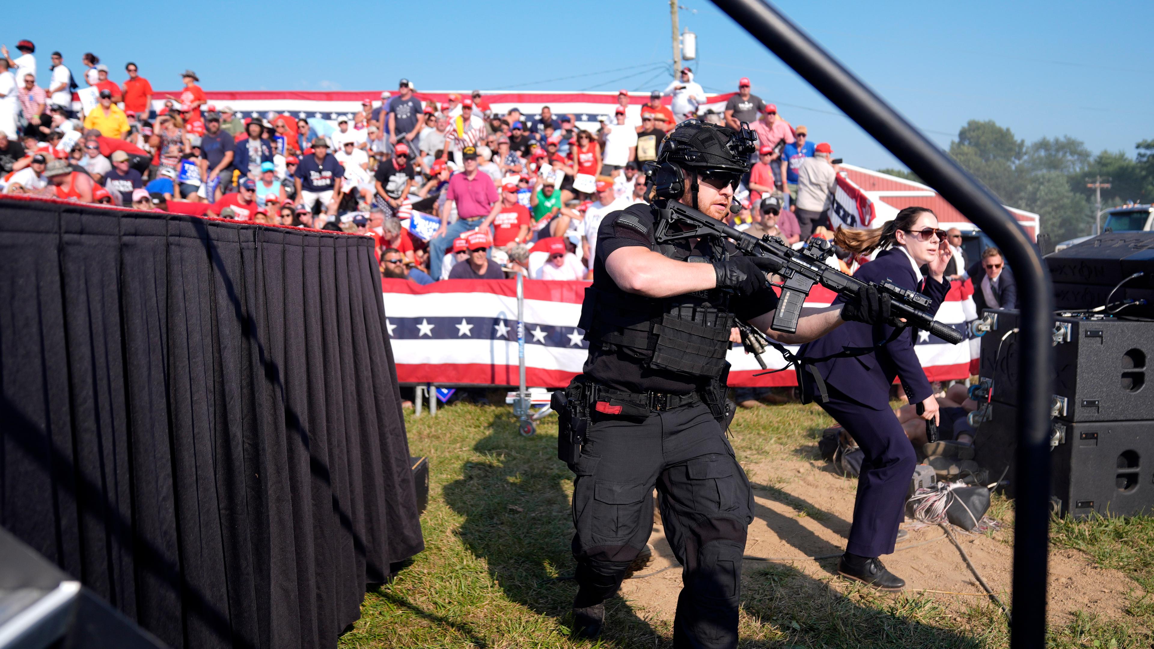 USA, Butler: Einsatzkräfte stürmen die Bühne während einer Wahlkampfveranstaltung mit dem republikanischen Präsidentschaftsbewerber und ehemaligen US-Präsidenten Donald Trump