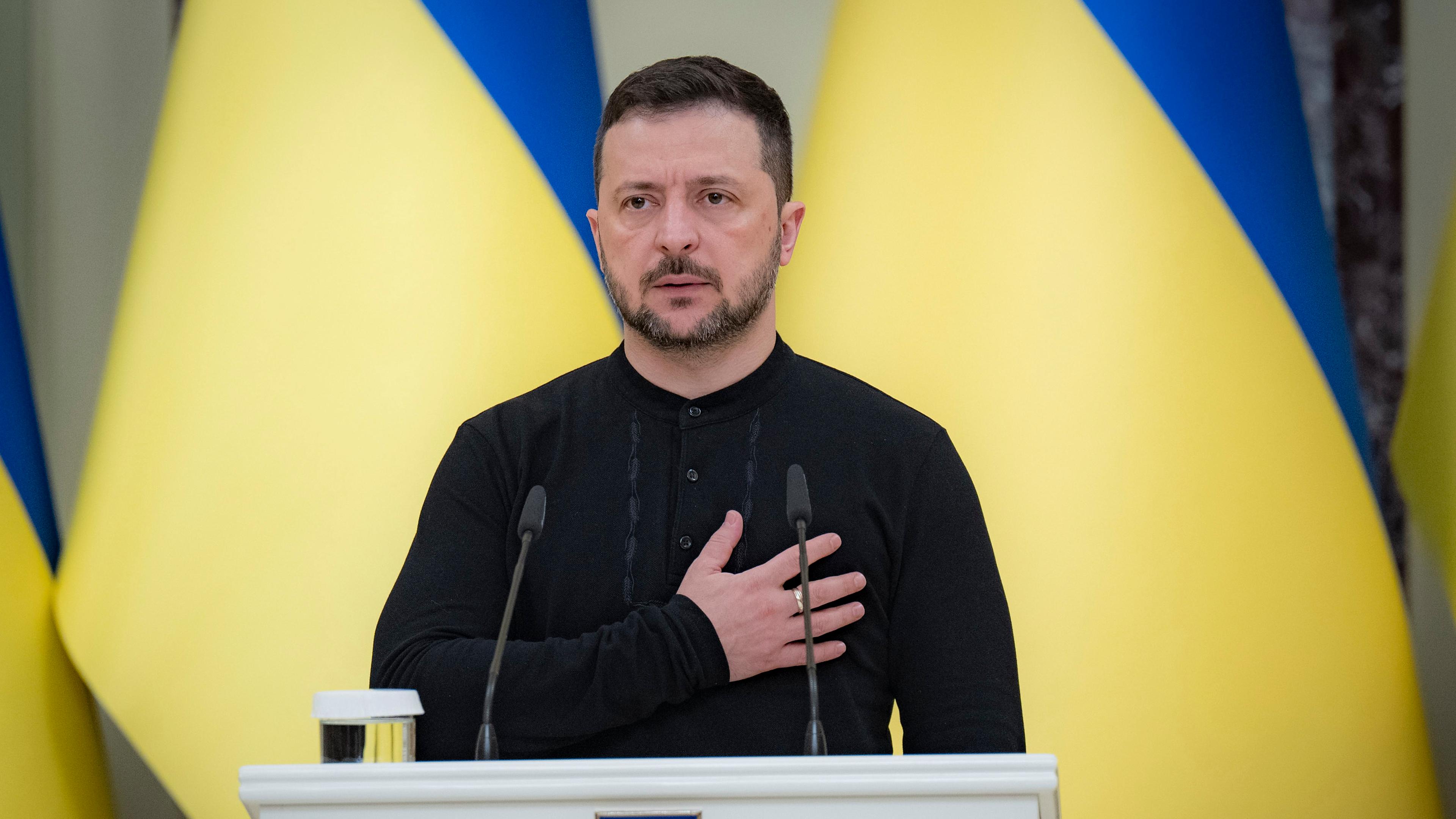 Ukraine, Kiew: Wolodymyr Selenskyj, Präsident der Ukraine, steht beim Abspielen der Nationalhymne, bevor er während einer Zeremonie im Mariinskyi-Palast den Helden der Ukraine und den Familien der gefallenen Soldaten Urkunden für kostenlose Wohnungen überreicht.