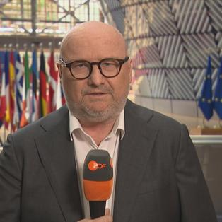 Ulf Röller im Europaparlament, hinter ihm viele verschieden europäische Flaggen.