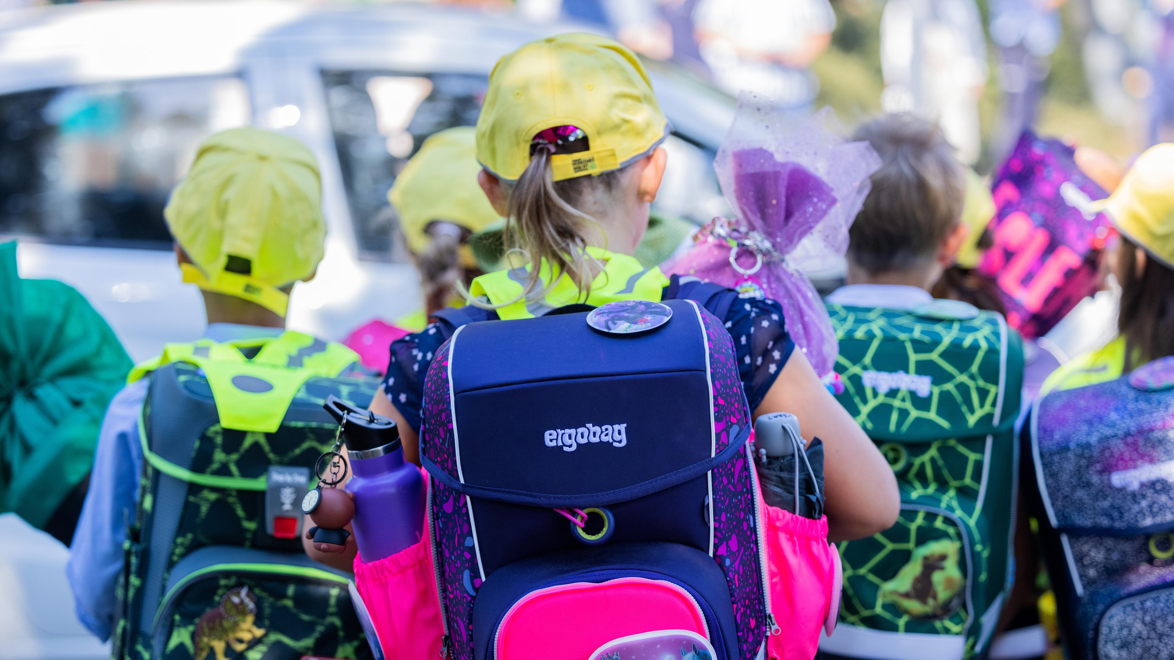 Erstklässler gehen mit Schulranzen und Schultüte zur Schule.