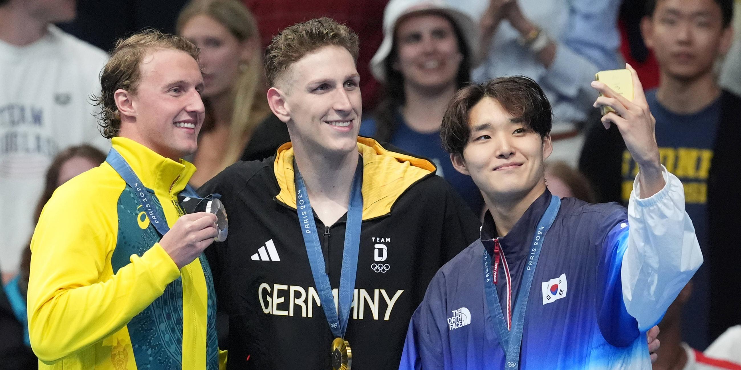 Der deutsche Goldmedaillengewinner Lukas Maertens (C), der australische Silbermedaillengewinner Elijah Winnington (L) und der südkoreanische Bronzemedaillengewinner Woomin Kim posieren mit ihren Medaillen.