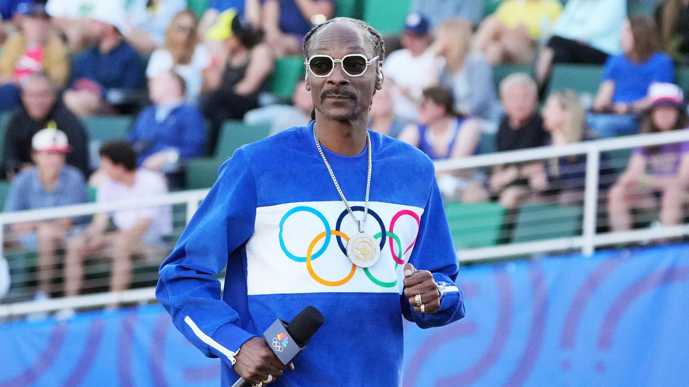 Der US-Rapper Snoop Dogg mit einem Pullover auf dem die olympischen Ringe zu sehen sind.