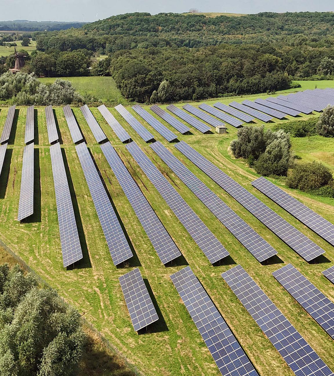 Sonnenkollektoren auf einem Solarfeld vor einem See in Neukirchen-Vluyn