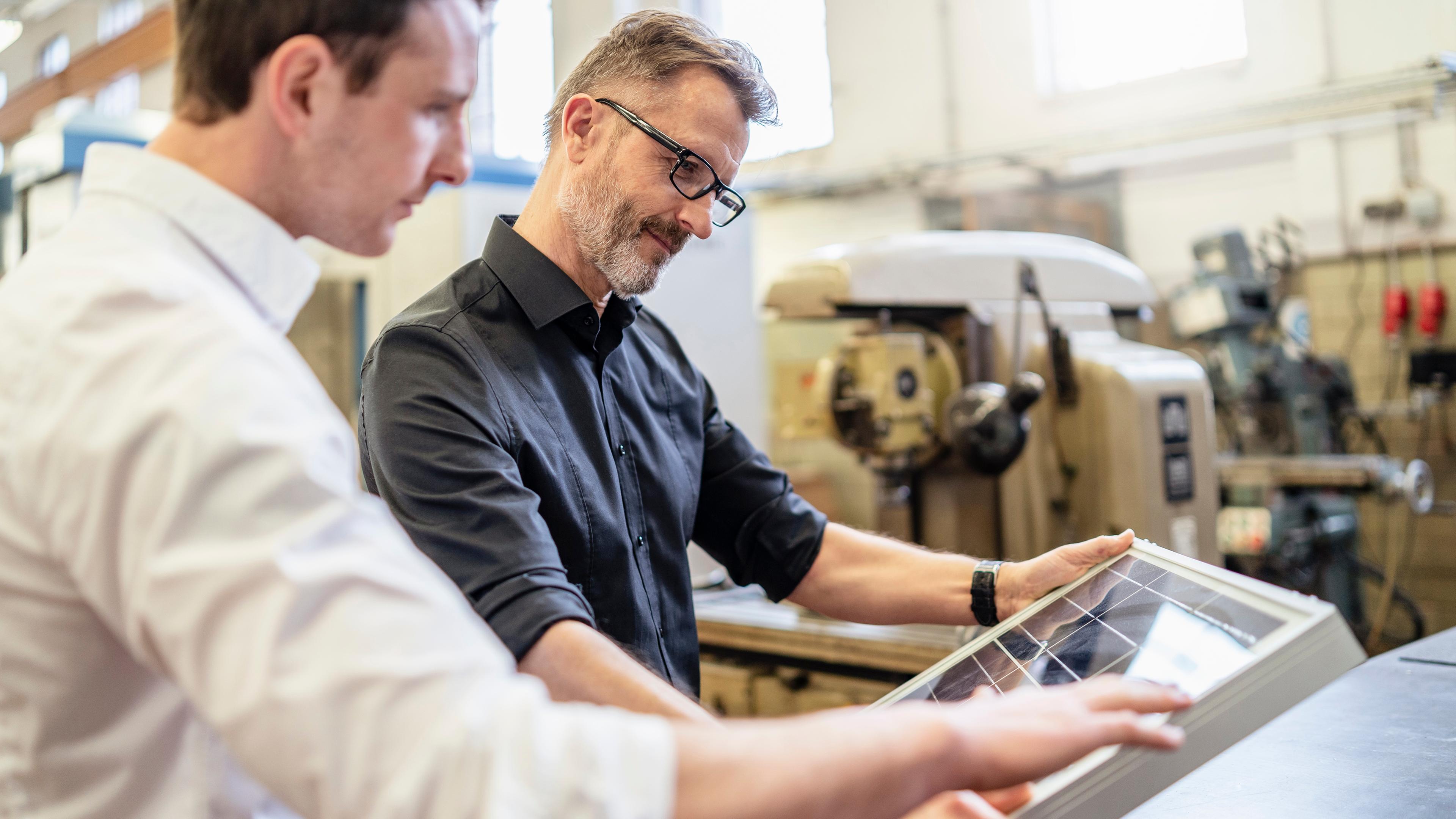 Zwei Kollegen arbeiten in der Fabrik an einer Solarzelle