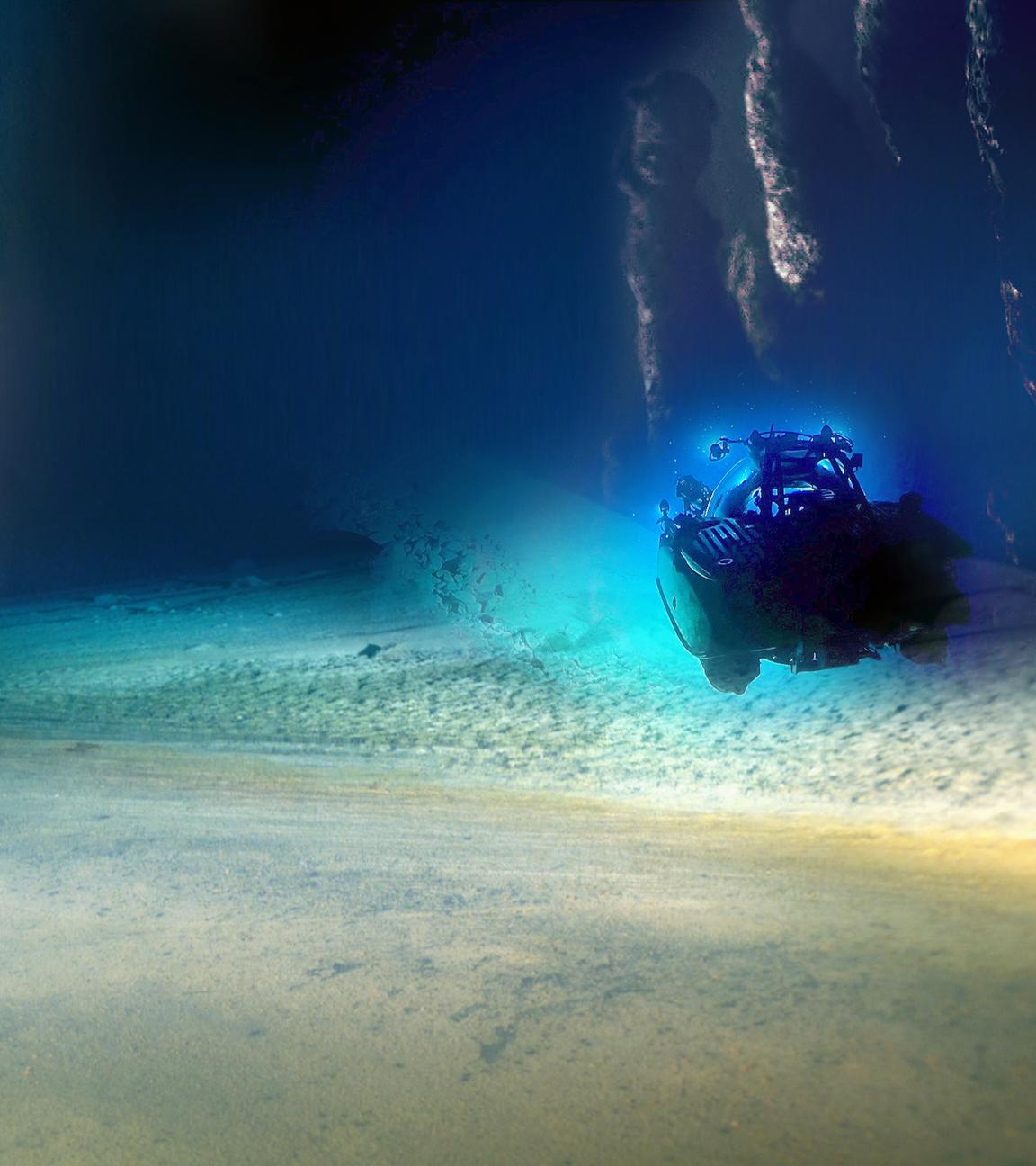 Blick auf türkis und blau leuchtende Felswände und einen Strand unter Wasser. Ein Tauchboot untersucht den Meeresgrund.