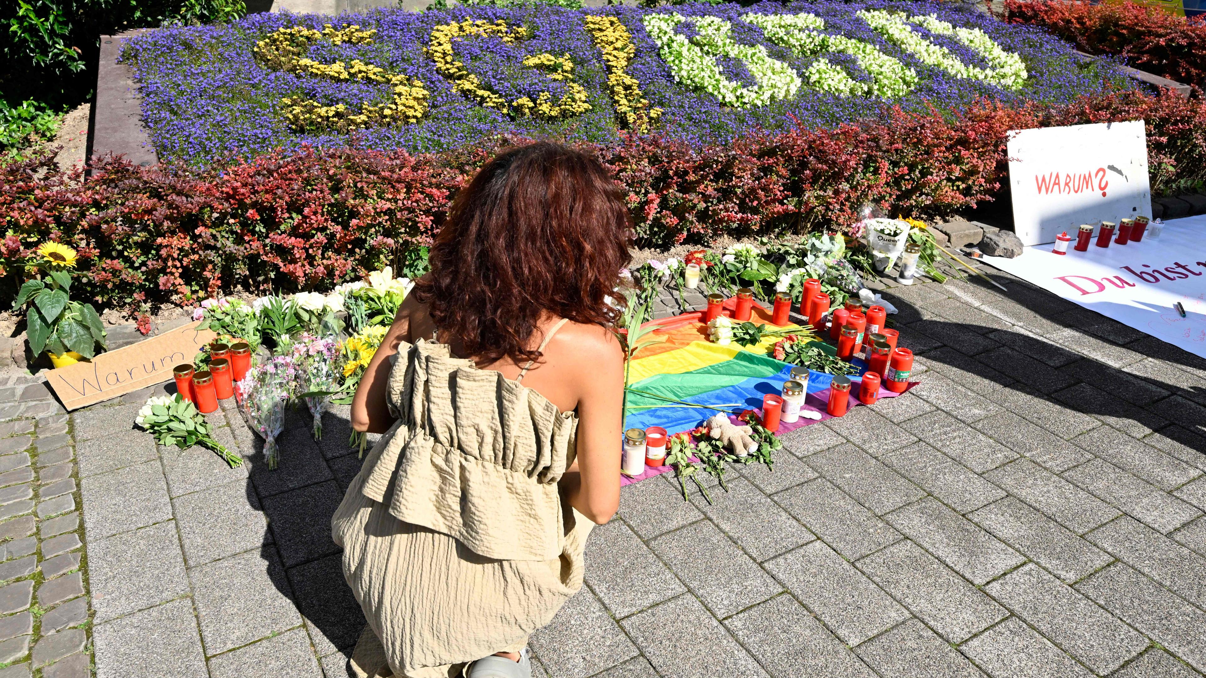 Eine Frau legt an einem Blumenbeet in Solingen mit "SG/ 650" Blumen nieder.