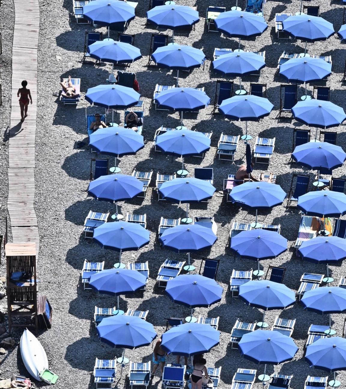 Blaue Sonnenschirme sind an italienischem Strand dicht beieinander aufgestellt