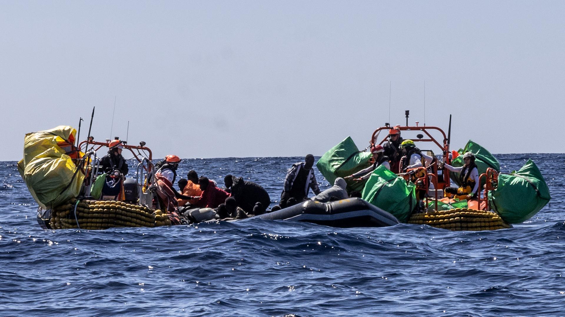 Das Rettungspersonal des humanitären SOS-Mediterranee-Schiffes Ocean Viking hilft Migranten bei der Evakuierung eines teilweise entleerten Schlauchboots im zentralen Mittelmeer.
