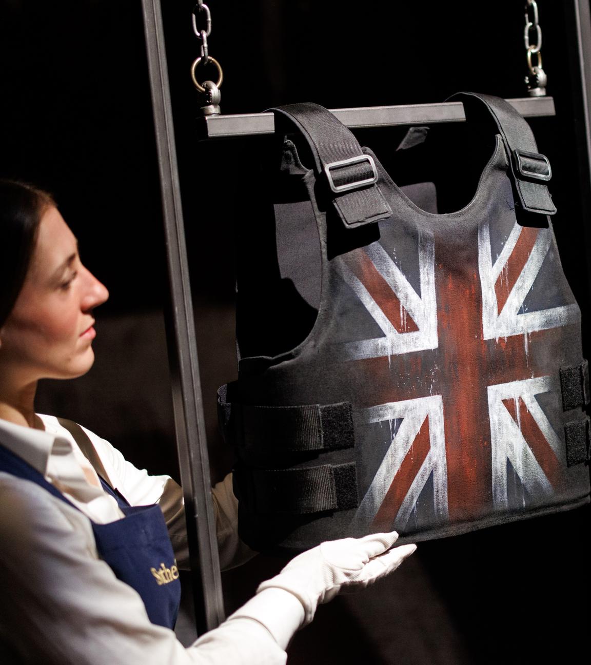 Ein Galeriepersonal posiert mit einem Kunstwerk mit dem Titel „Vest“ des britischen Künstlers Banksy während einer Fotoausstellung im Auktionshaus Sotheby's in London, Großbritannien, am 4. Oktober 2024.