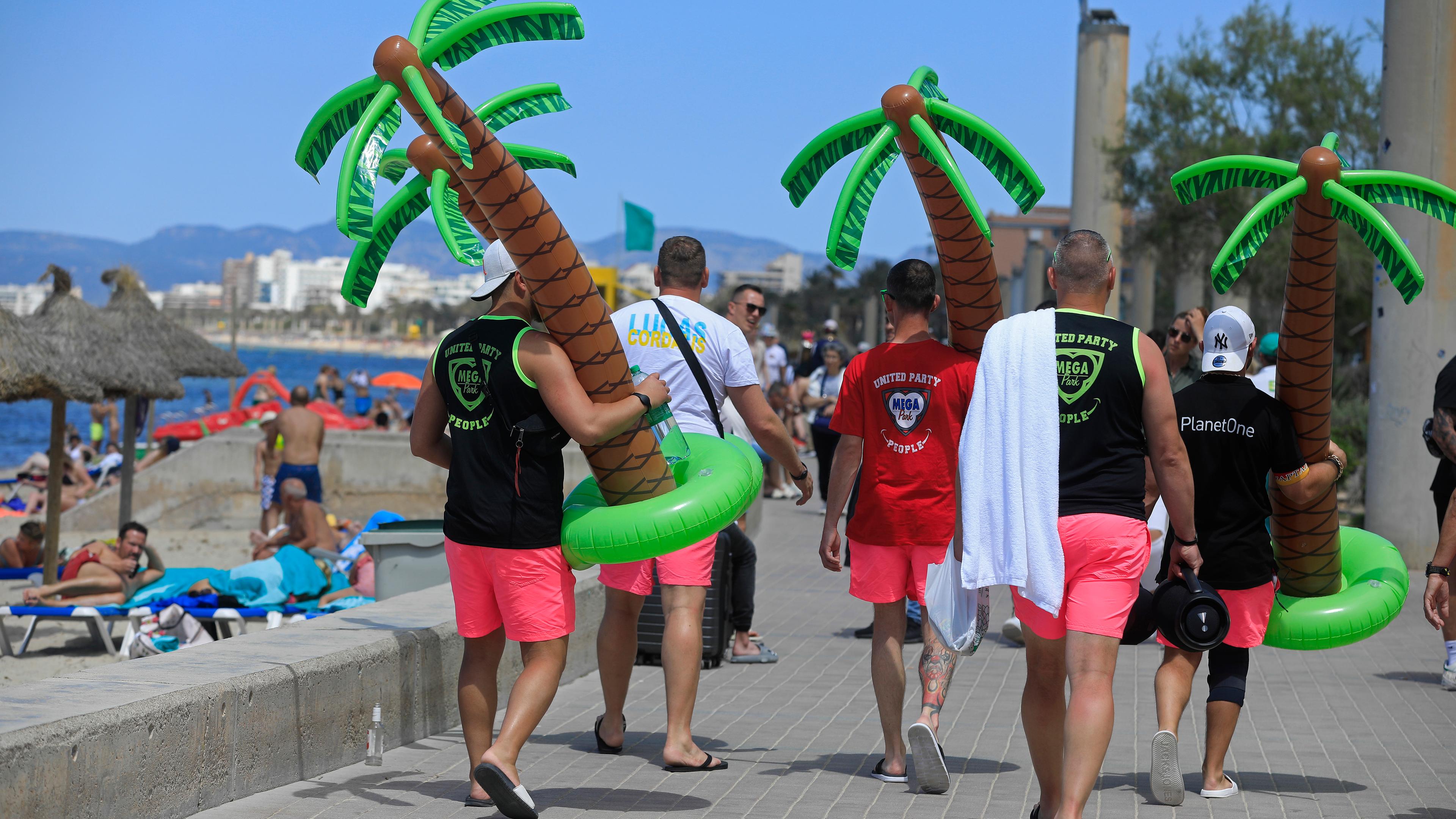 Spanien, Palma: Männer tragen an einem sonnigen Tag Plastikpalmen am Strand Arenal. Archivbild