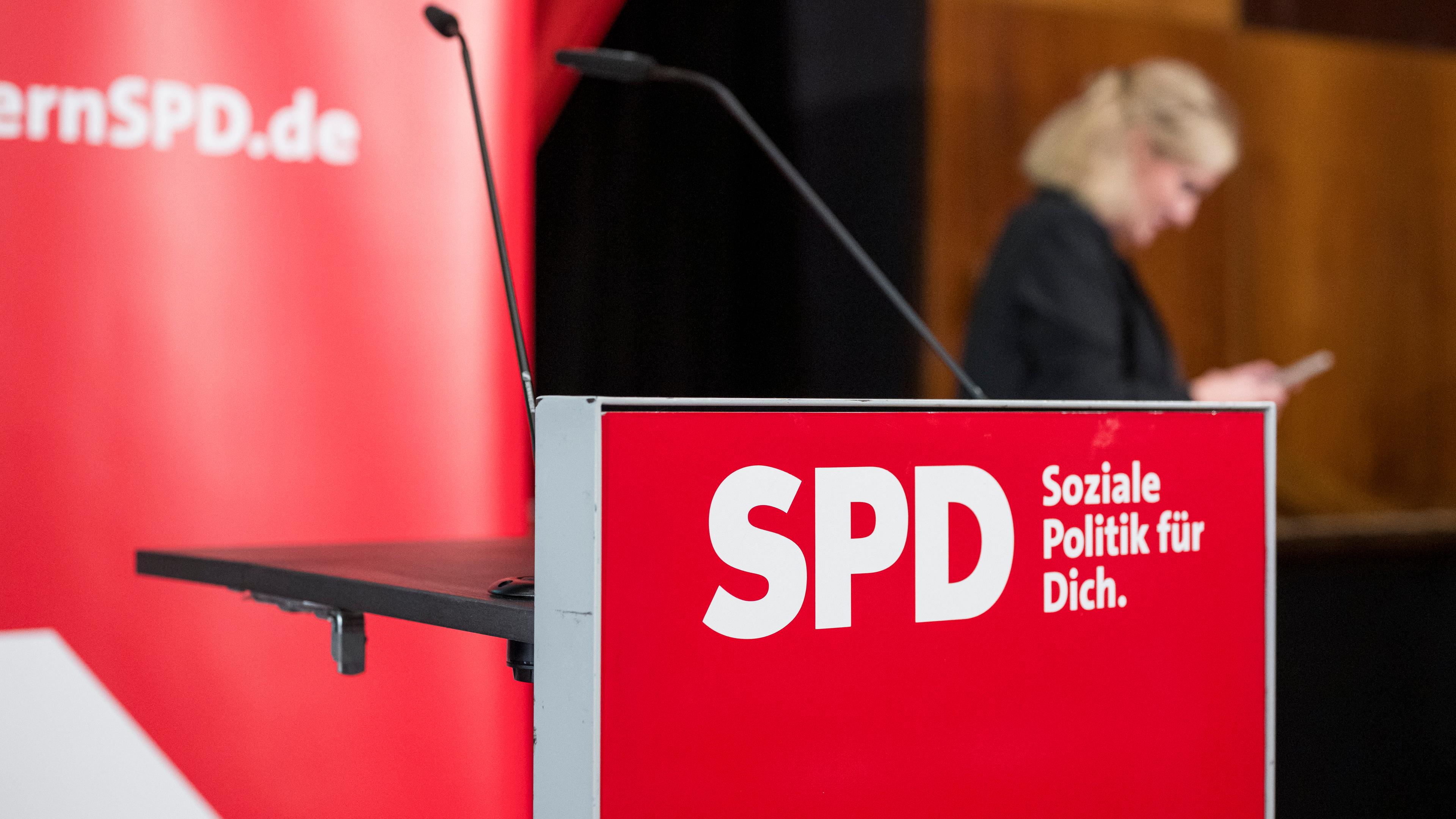 SPD-Rednerpult mit verschwommener Frau und SPD-Plakat im Hintergrund