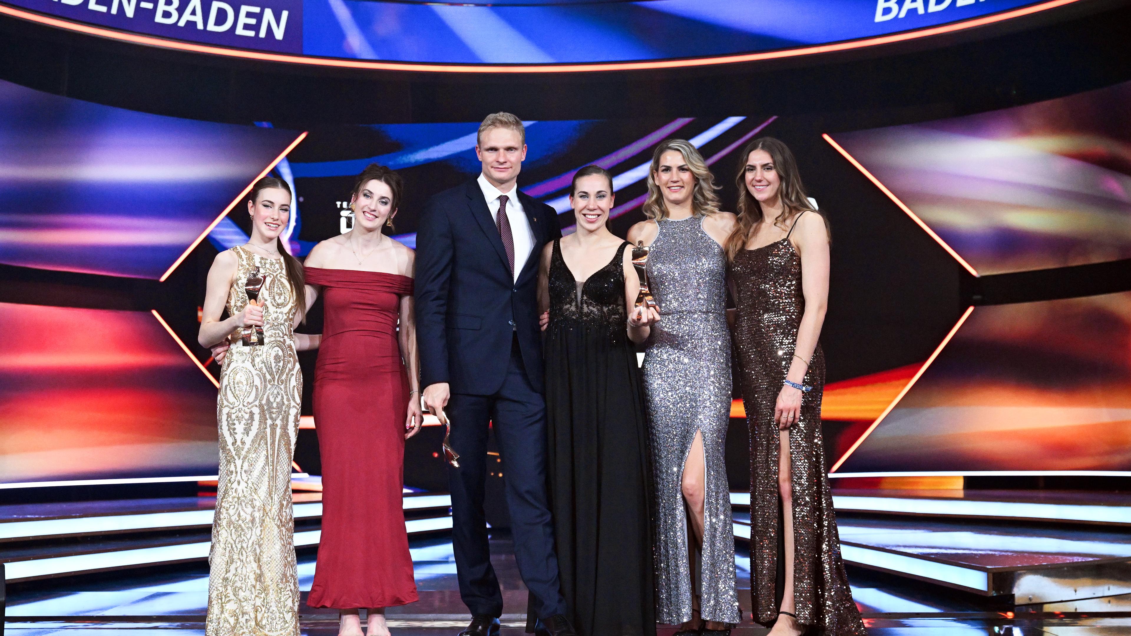 Baden-Württemberg, Baden-Baden: Die Sportgymnastin Darja Varfolomeev (l), der Ruderer Oliver Zeidler (3.v.l) und die 3x3-Basketballerinnen Elisa Mevius (2.v.l), Svenja Brunckhorst (M-r), Sonja Greinacher und Marie Reichert stehen während der Gala für die Wahl «Sportler des Jahres» im Kurhaus mit ihren Siegertrophäen auf der Bühne. 