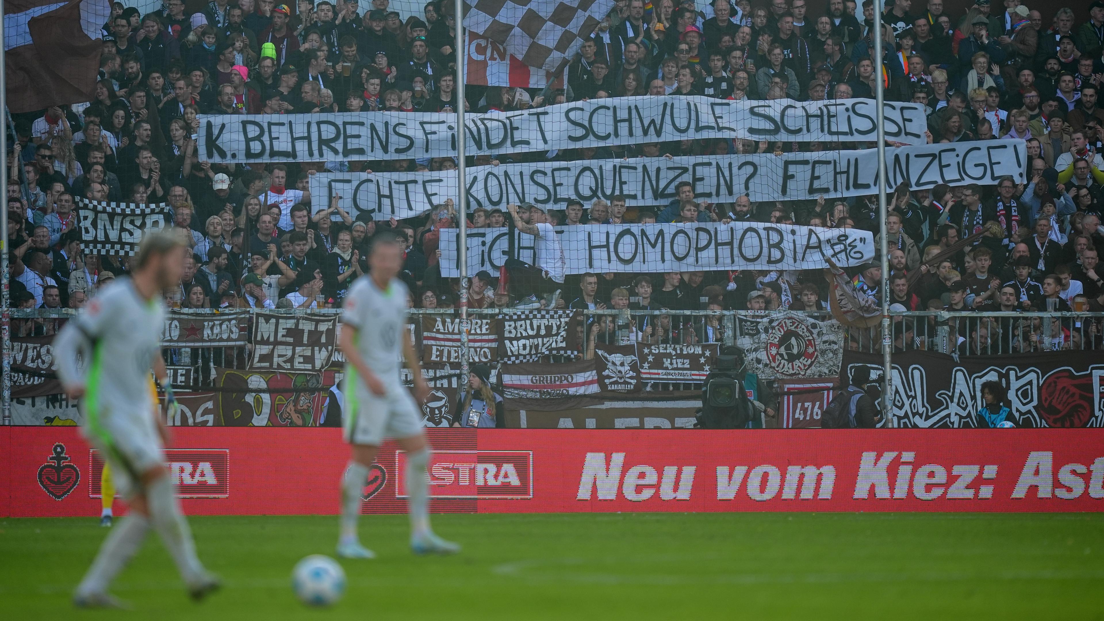 Fans halten Plakate nach den homophoben Aussagen des Wolfsburger Stürmers Kevin Behrens hoch. 